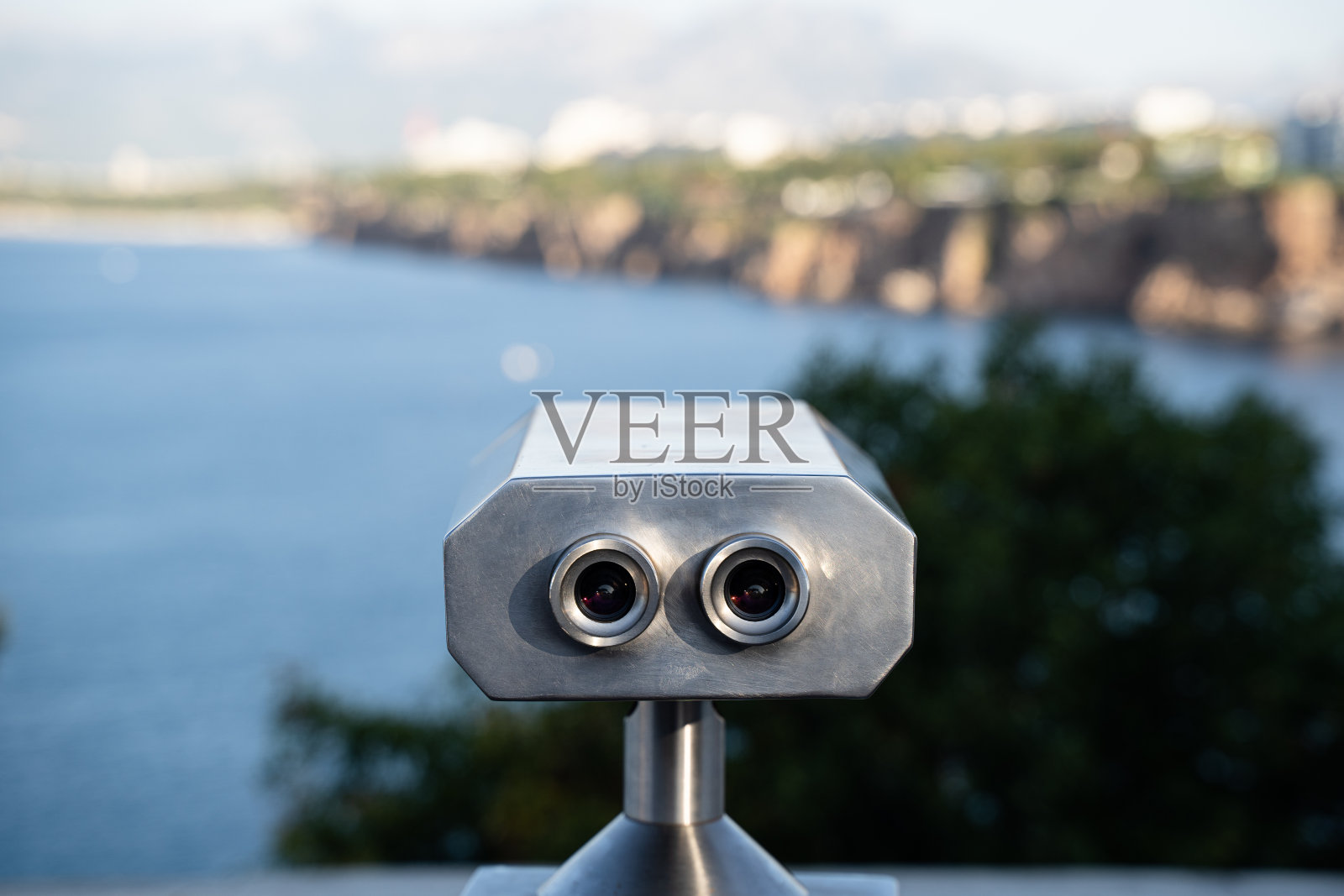 硬币在山和海前操作双筒望远镜照片摄影图片