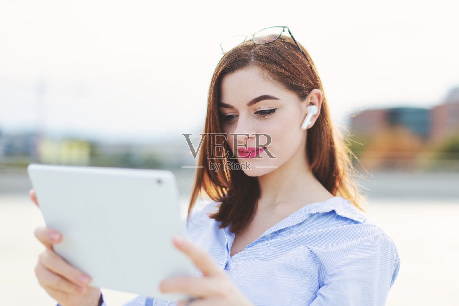 年轻的20多岁的女人戴着耳机在户外使用平板电脑照片摄影图片