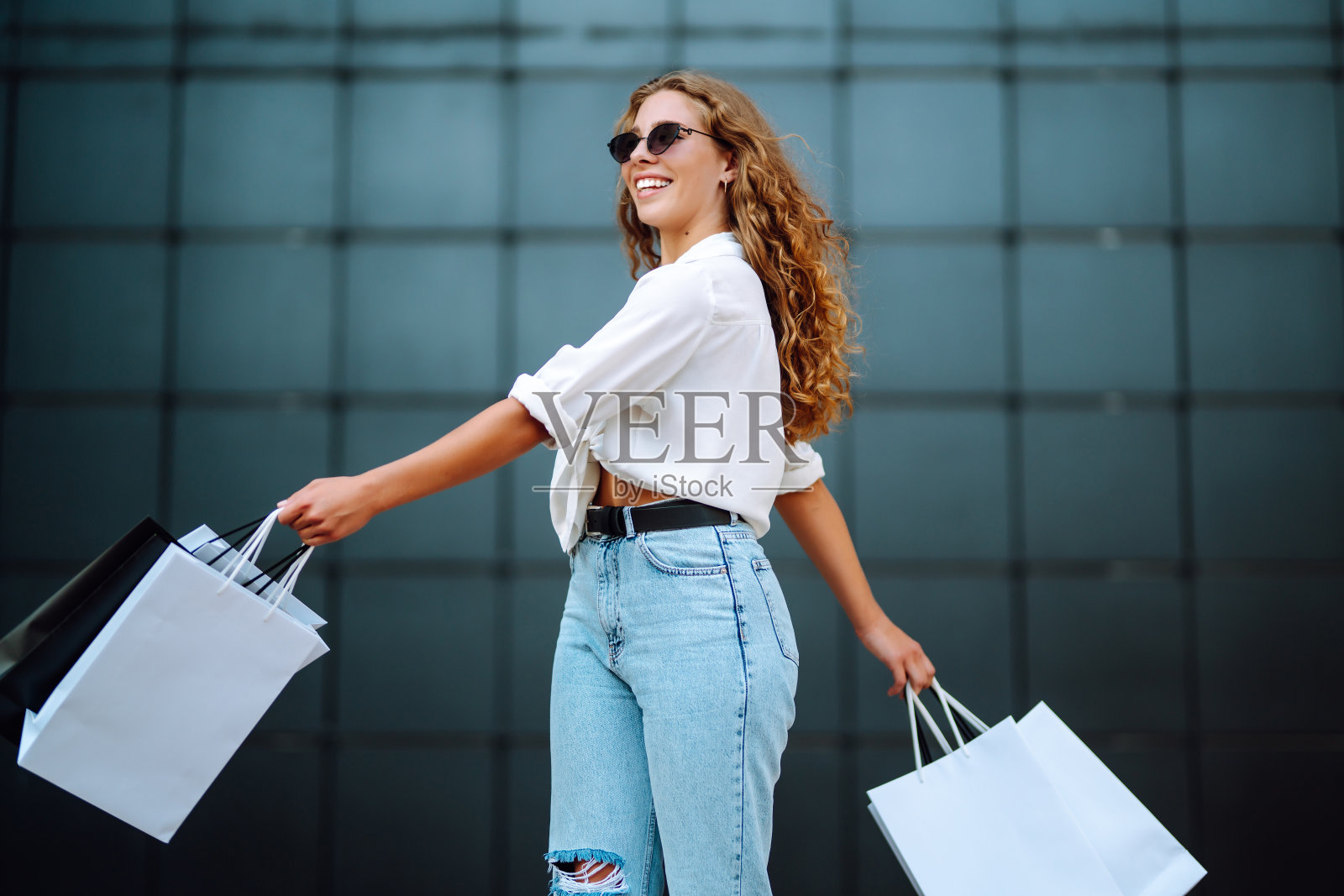 一个女人提着购物袋走在城市的街道上。“黑色星期五”。照片摄影图片