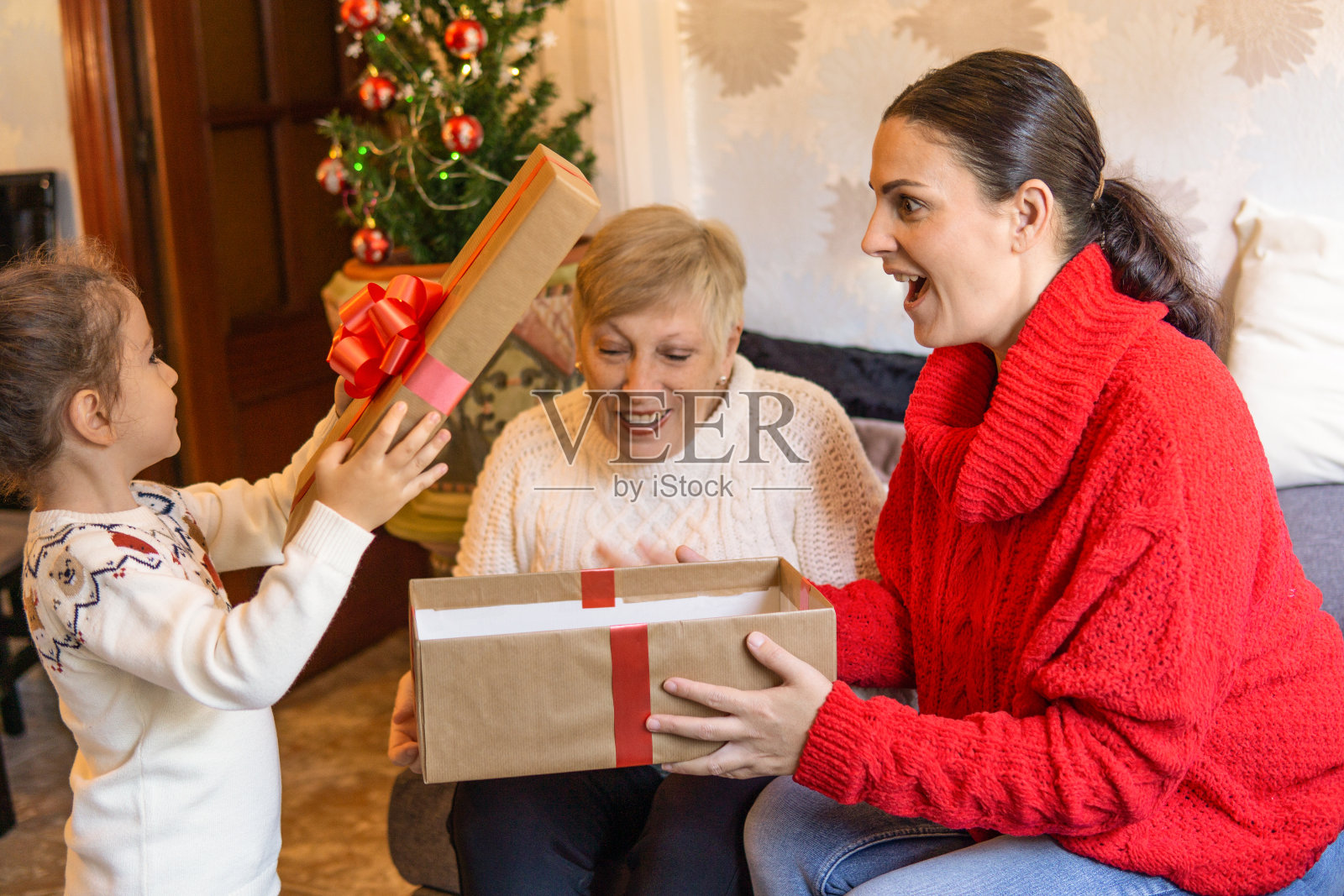 孩子和家人一起打开圣诞礼物。礼品包在可回收的纸照片摄影图片