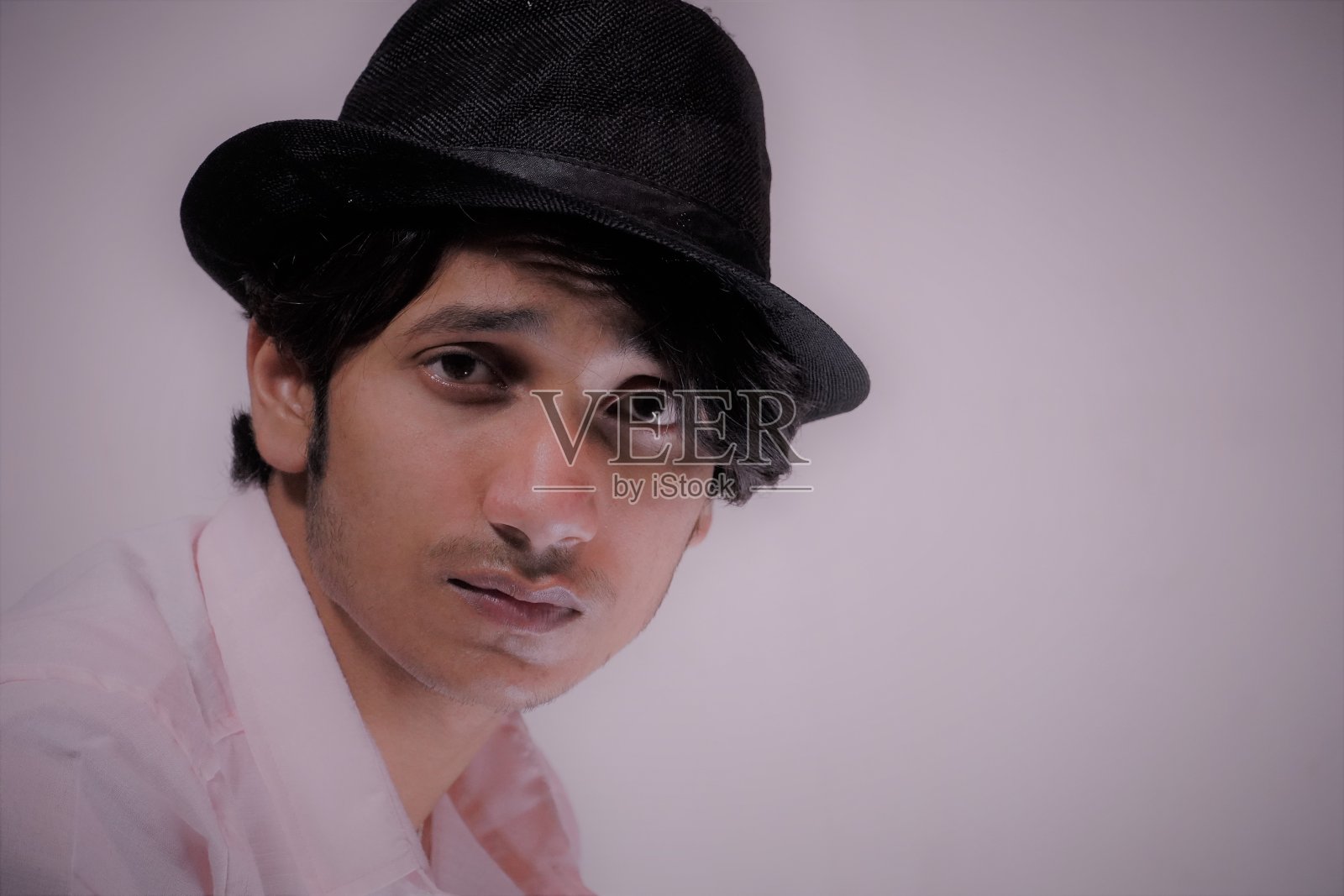 近距离的肖像微笑英俊的男子，穿着粉红色的衬衫和黑色的帽子。照片摄影图片