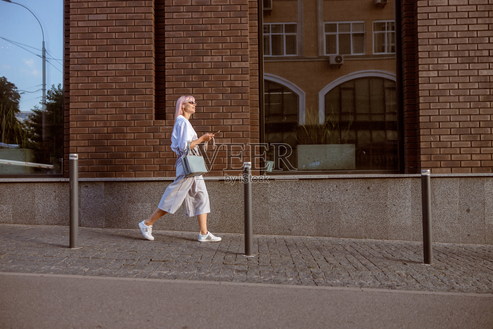 年轻女子拿着智能手机走在街上照片摄影图片