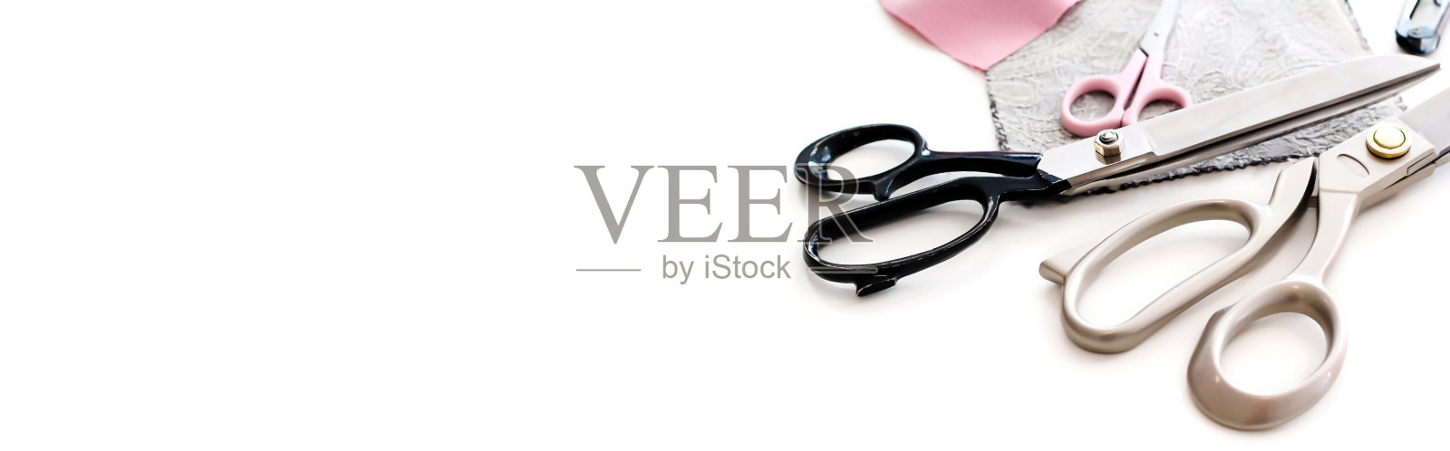 裁缝用的剪刀放在桌子上，旁边是碎布片。一个网站的横幅，一个放置文本的地方。照片摄影图片