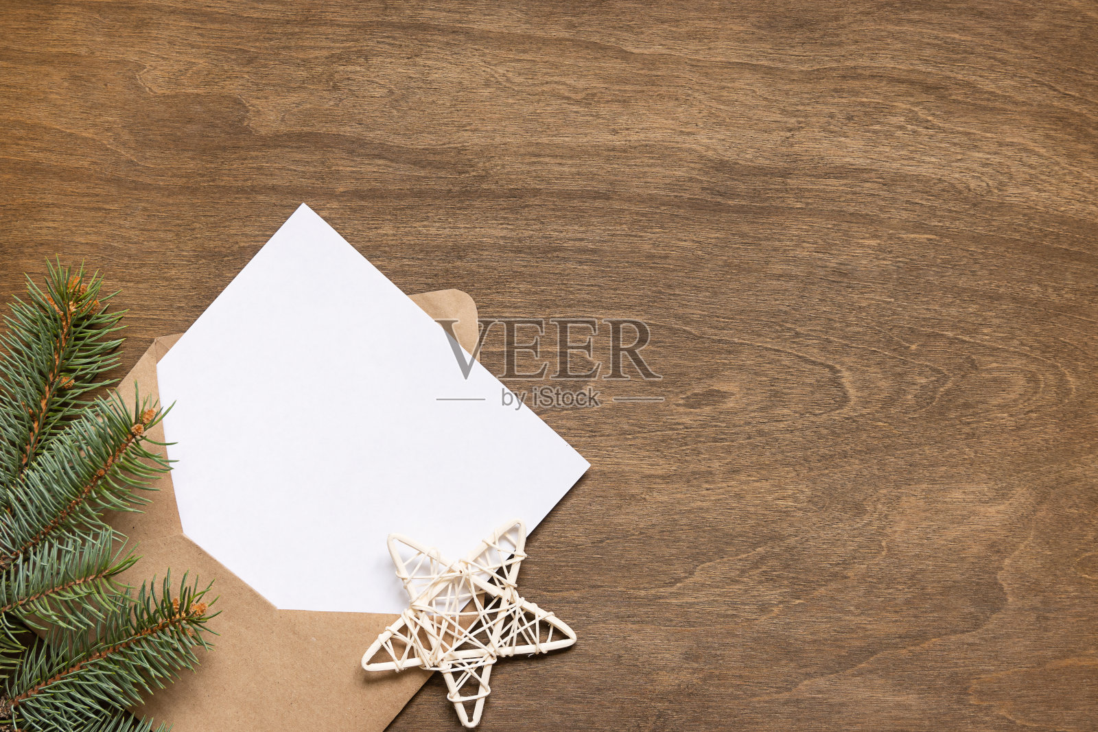 装着一封信的信封放在一张木桌上，木桌上有云杉树枝和木制星星照片摄影图片