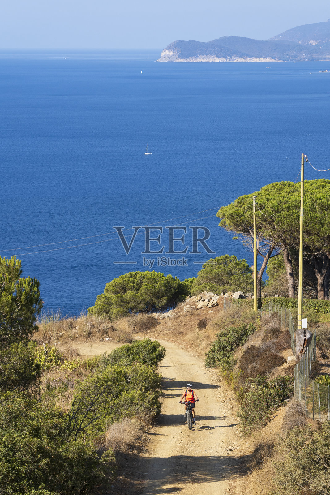 在意大利托斯卡纳的厄尔巴岛的海岸线上，一名女子骑着电动登山车照片摄影图片