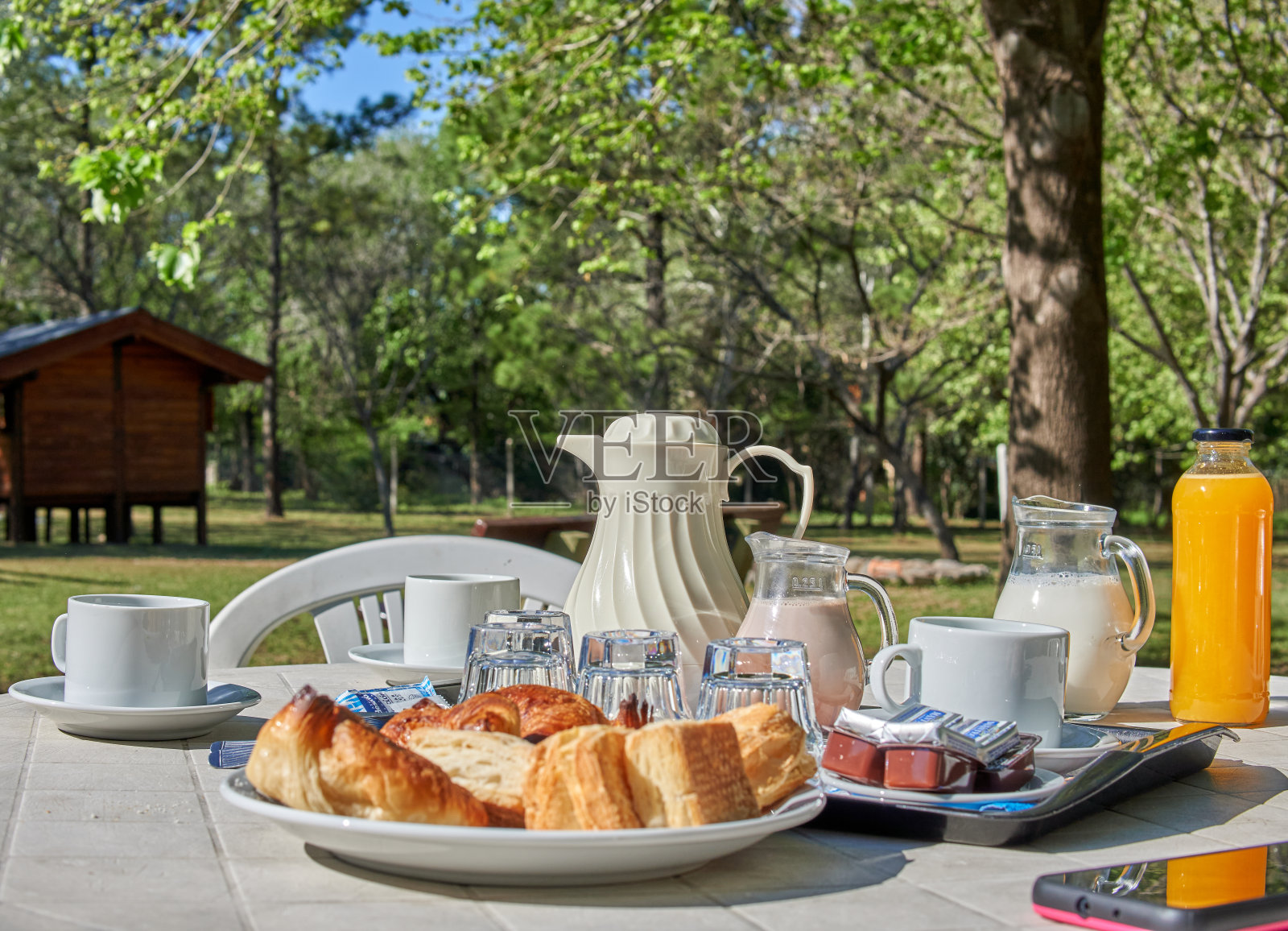 假日花园中的阿根廷早餐。饼干，羊角面包，橙汁，牛奶，咖啡。水平的。模糊的背景照片摄影图片
