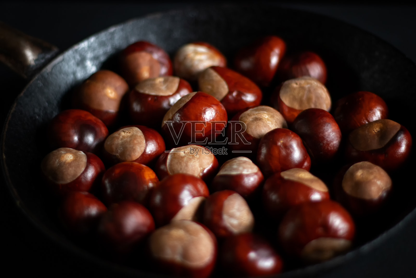 老铁锅里的熟栗子。照片摄影图片