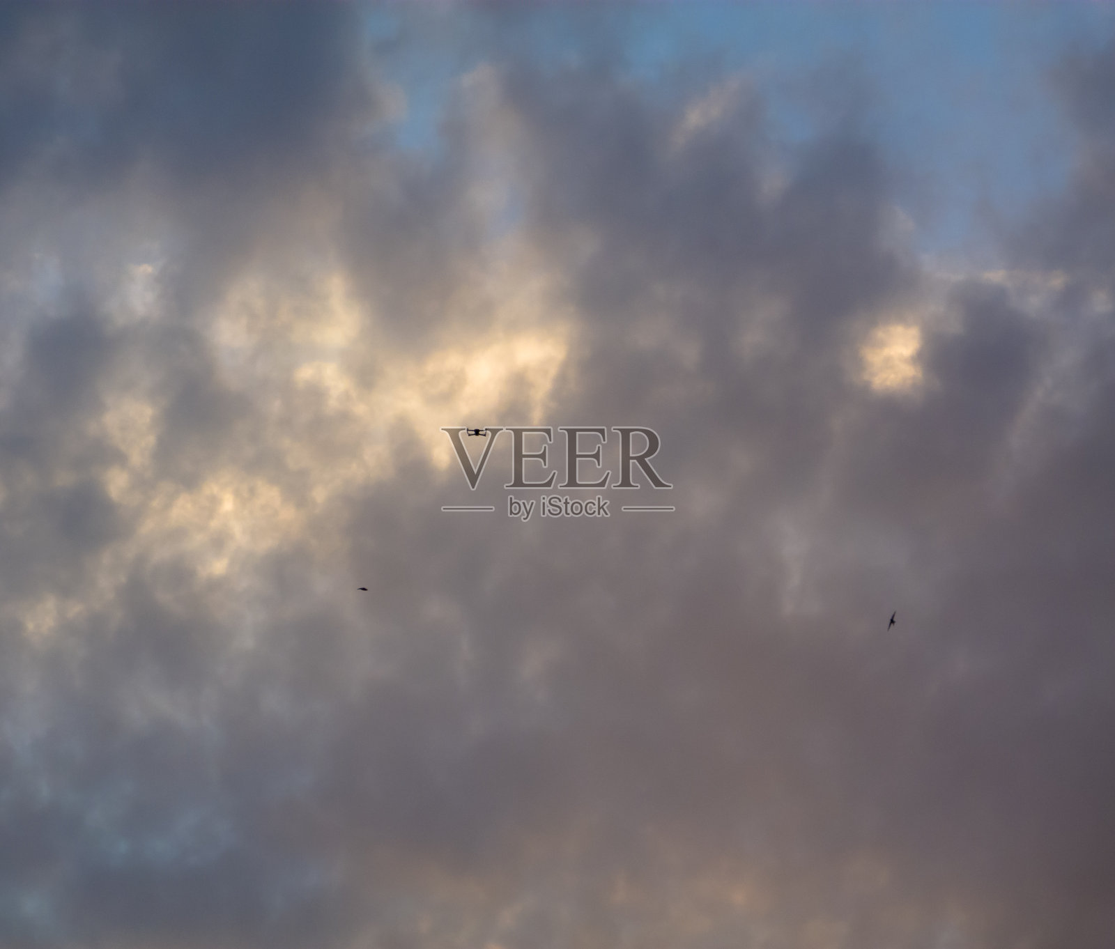 日落时多云的天空，伴着鸟儿和无人机照片摄影图片