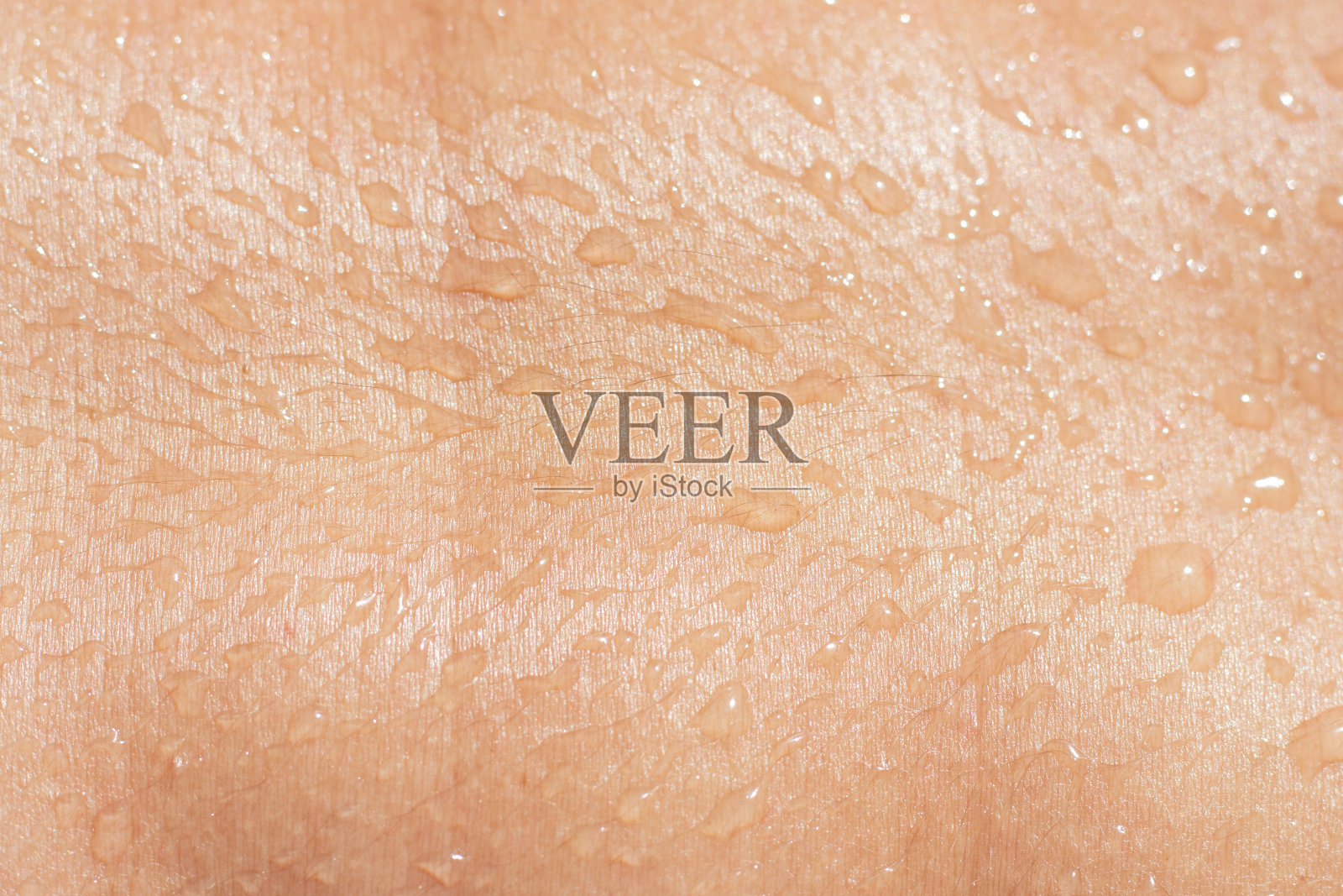 湿女性皮肤纹理与液体滴近距离。被水珠晒黑的人体。照片摄影图片