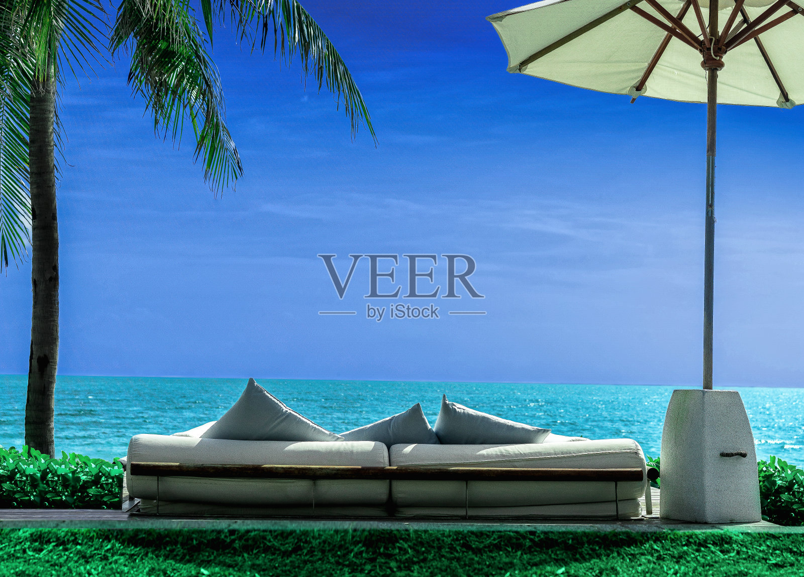 沙发椅俯瞰海滩，大海，沙滩伞，椰子树和绿色的草地。蓝天碧草照片摄影图片