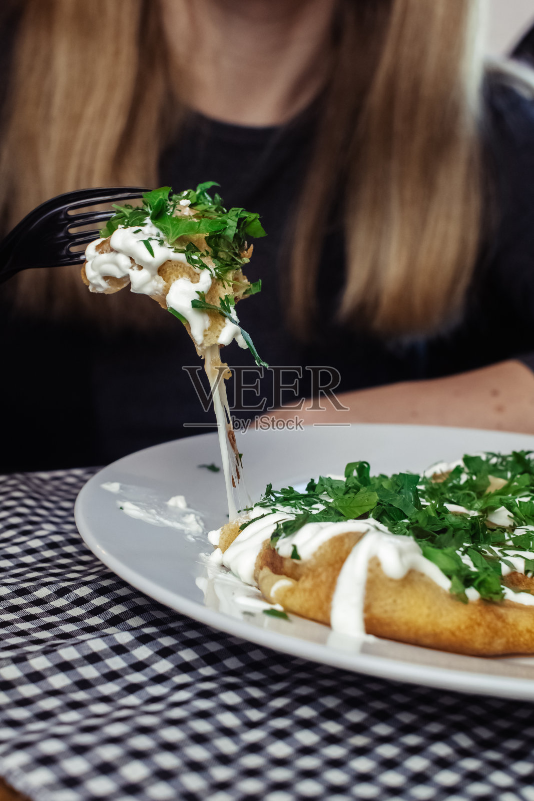 餐厅里盘子里有奶酪的薄饼。在咖啡馆吃早餐。一位妇女用一次性盘子吃煎饼当早餐。俯视图和垂直照片照片摄影图片