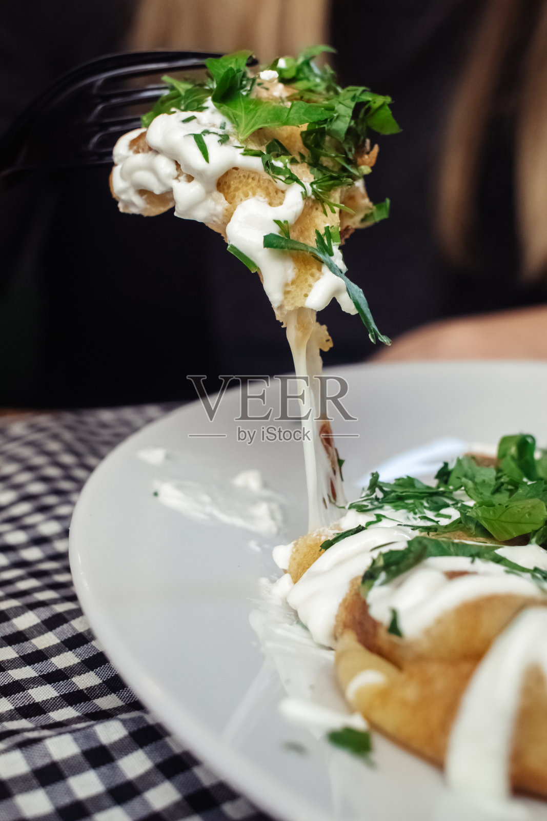 餐厅里盘子里有奶酪的薄饼。在咖啡馆吃早餐。一位妇女用一次性盘子吃煎饼当早餐。俯视图和垂直照片照片摄影图片