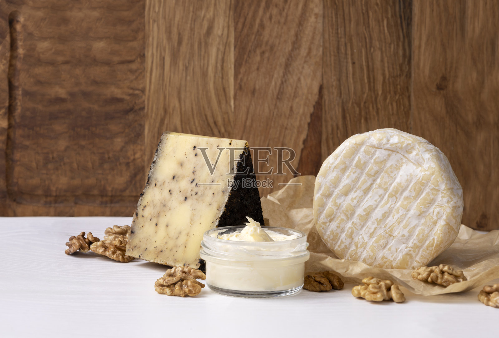 美味的卡门培尔乳酪，甜软的乳酪，传统的乳酪配乳酪，威士忌，胡桃木背景的白色桌子。空的空间照片摄影图片