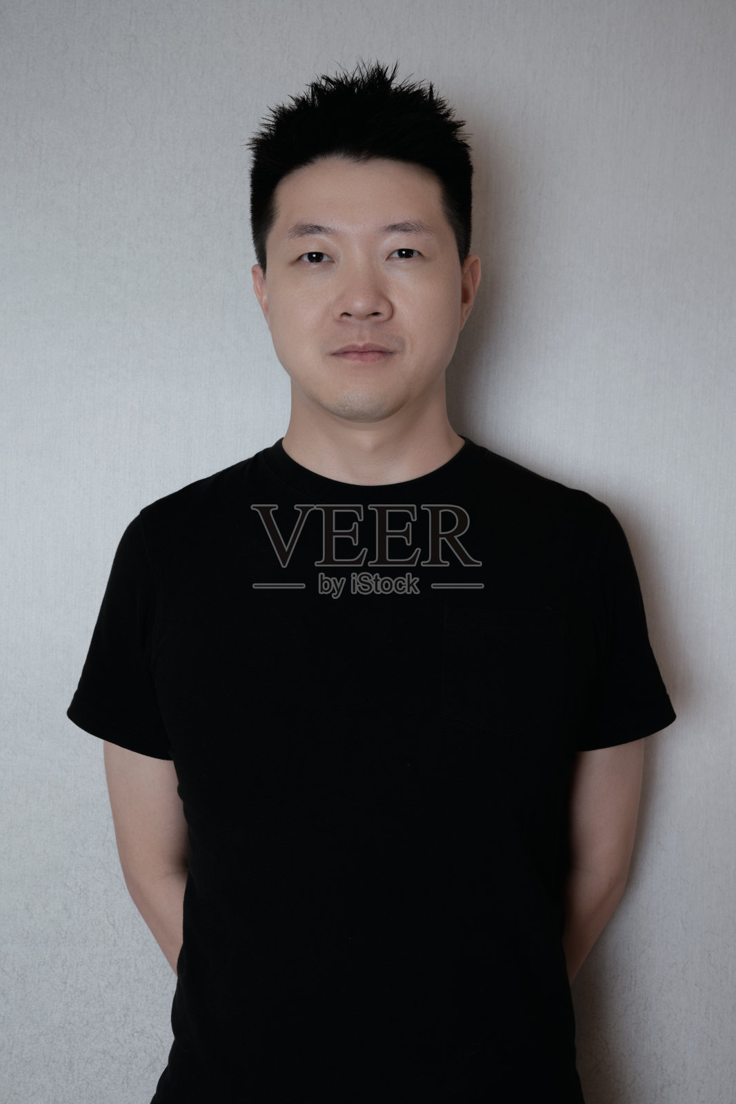 一个黑衣男人靠墙站着照片摄影图片