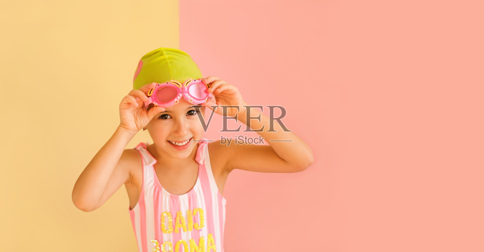 孩子戴着泳池帽，戴着游泳眼镜，在演播室背景中与世隔绝。照片摄影图片