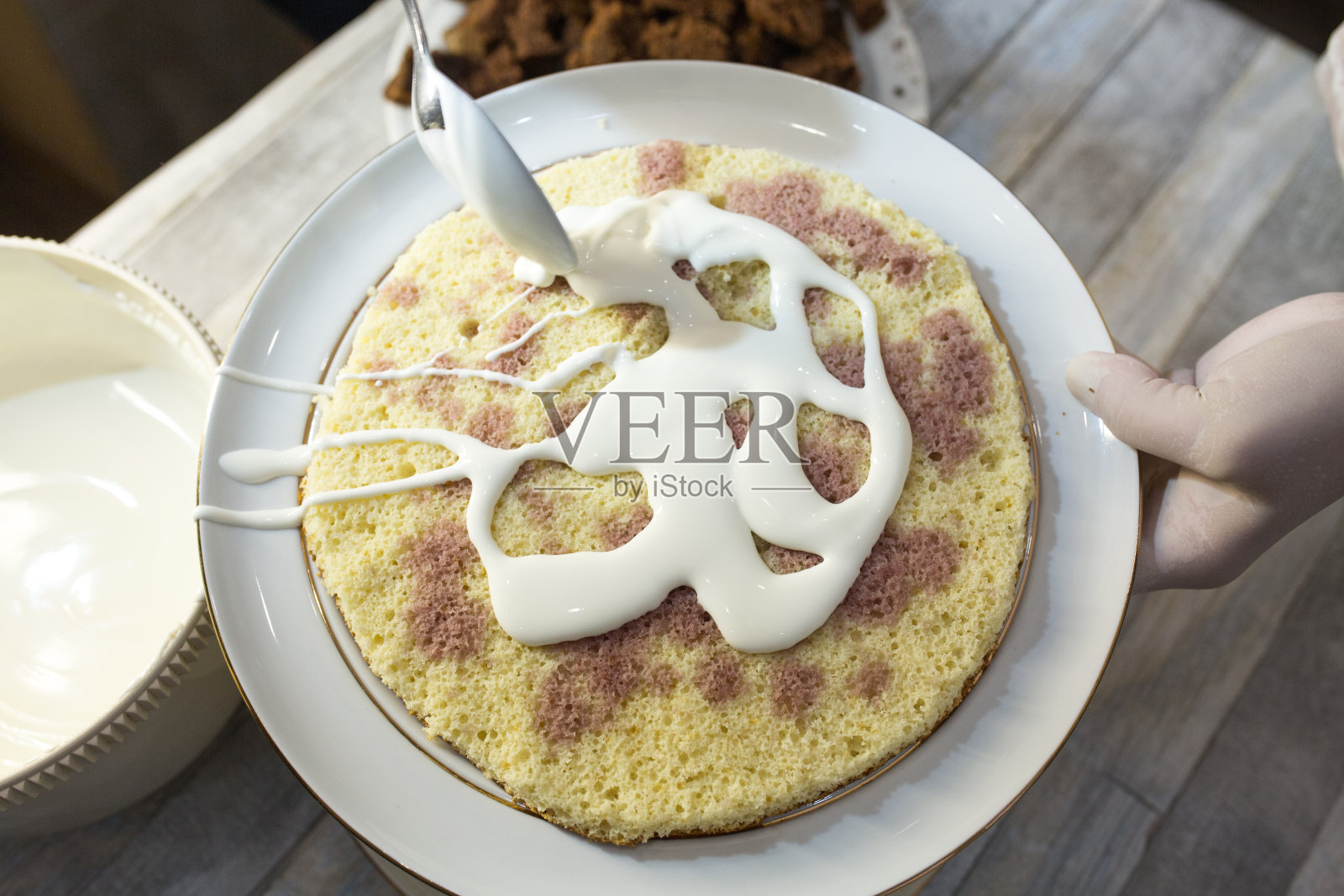 制作酸奶油巧克力蛋糕的步骤。形成了蛋糕。巧克力蛋糕被弄成小块，涂上酸奶油。照片摄影图片