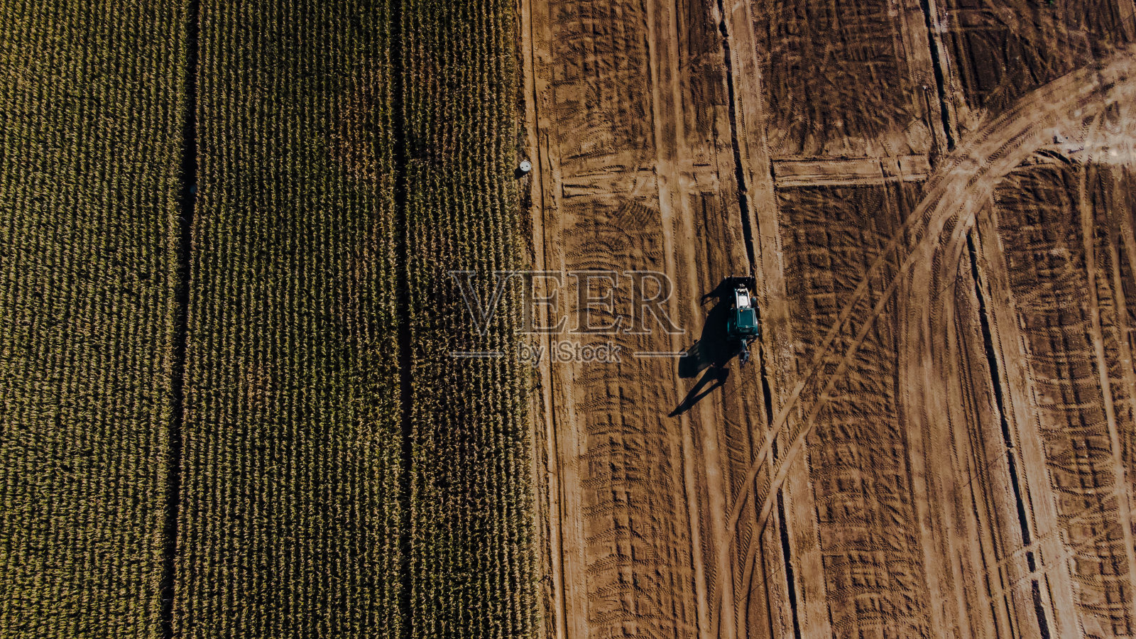 鸟瞰图拖拉机在耕地旁边的另一块田照片摄影图片