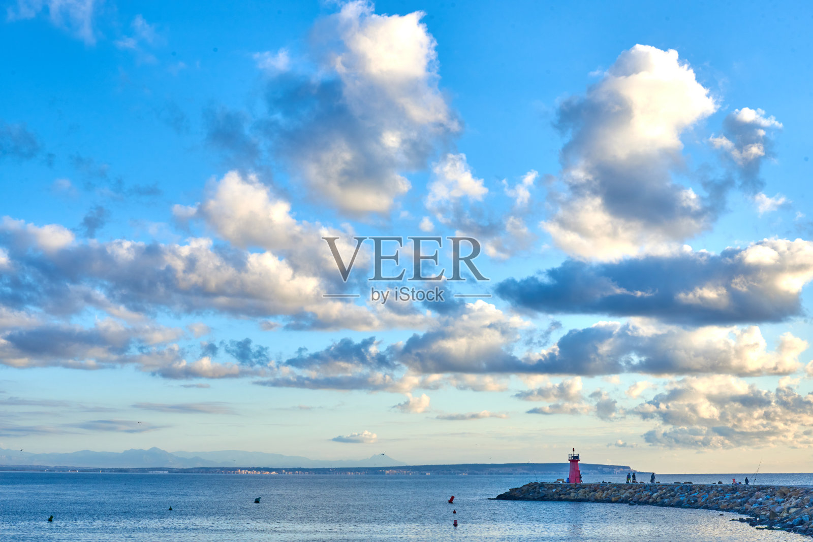 日出时在灯塔的防波堤上看着渔民照片摄影图片