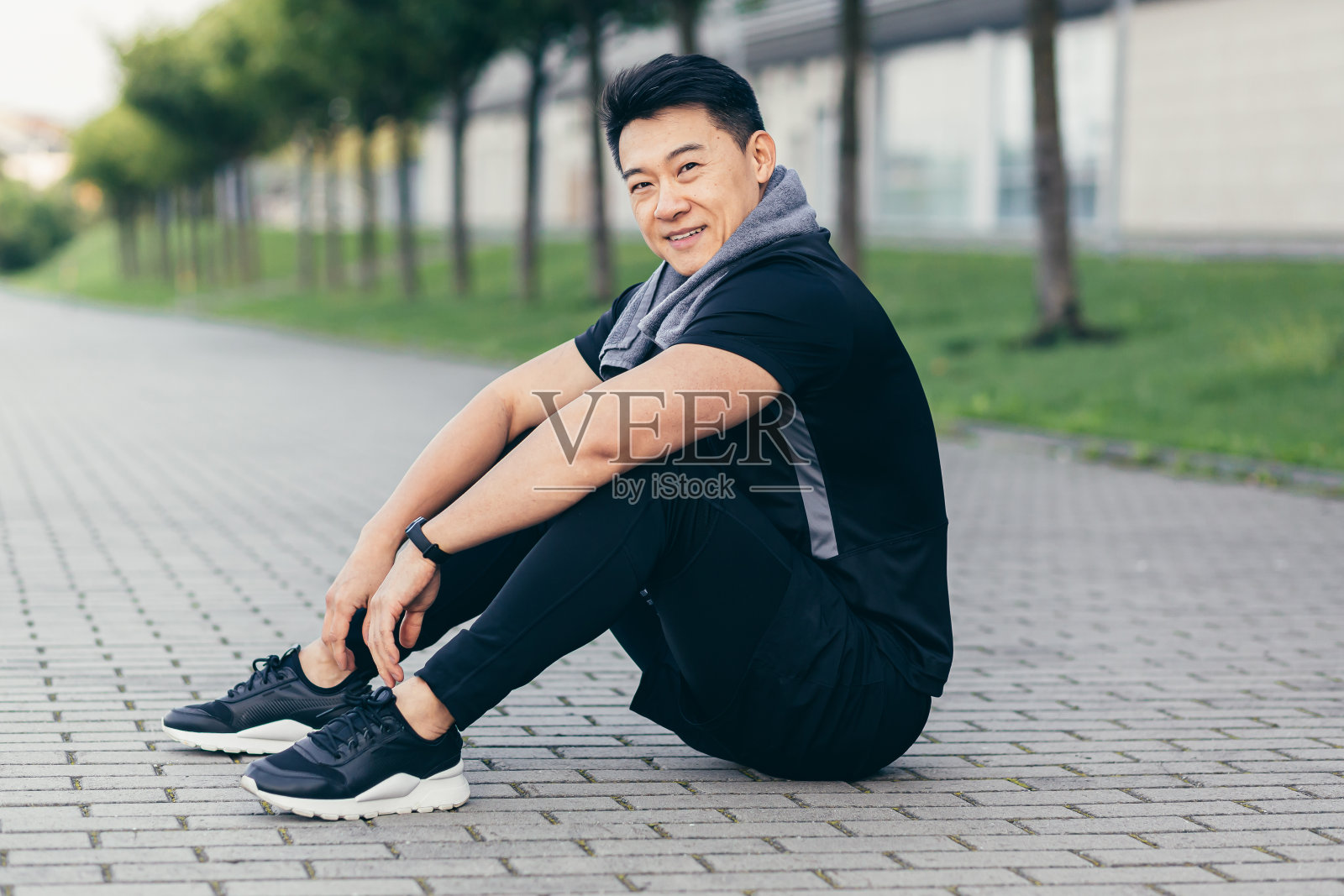 亚洲男性健身锻炼和慢跑后疲惫地坐在地上休息照片摄影图片