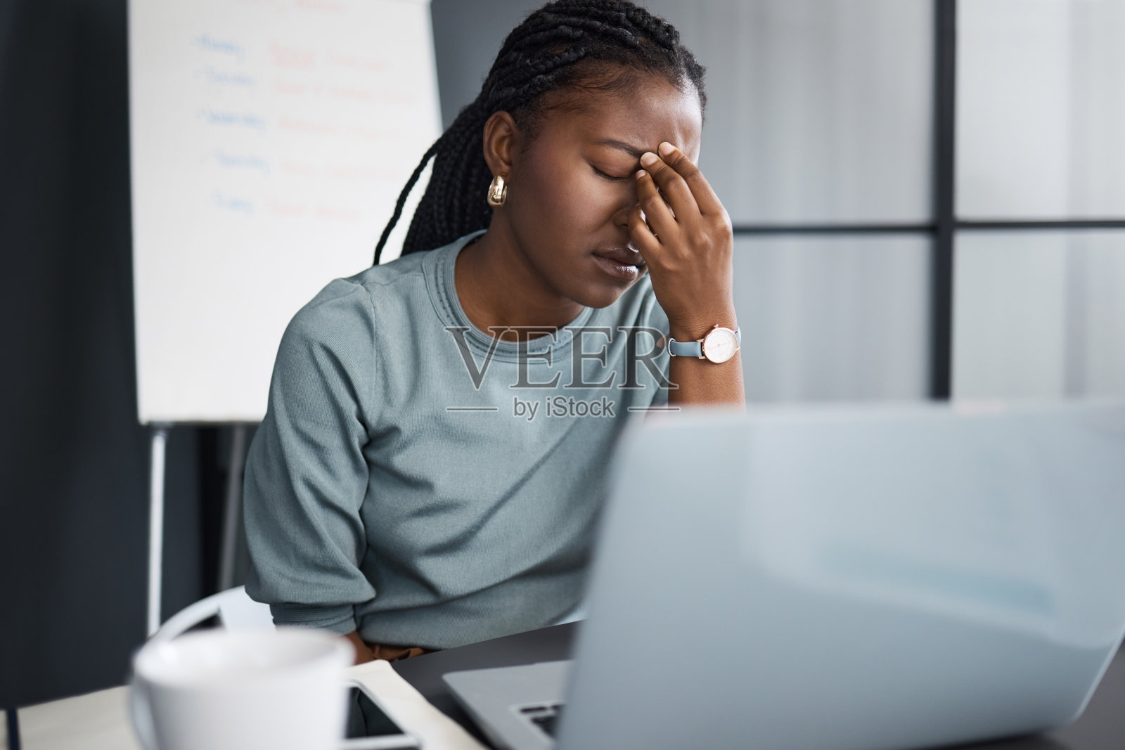 一名年轻的女商人在办公室里用笔记本电脑工作，看上去压力很大照片摄影图片