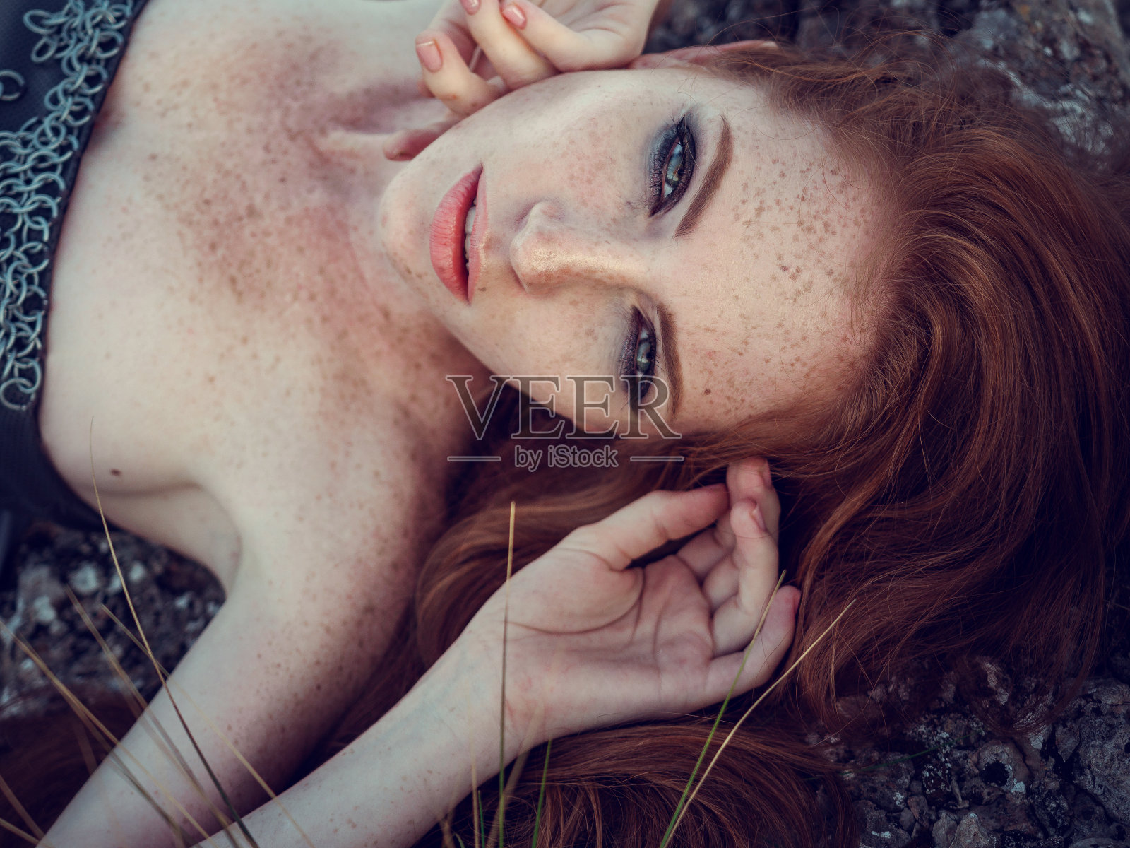 夏日户外肖像美丽的愤怒的斯堪的纳维亚战士姜女子灰色连衣裙与金属链甲。照片摄影图片