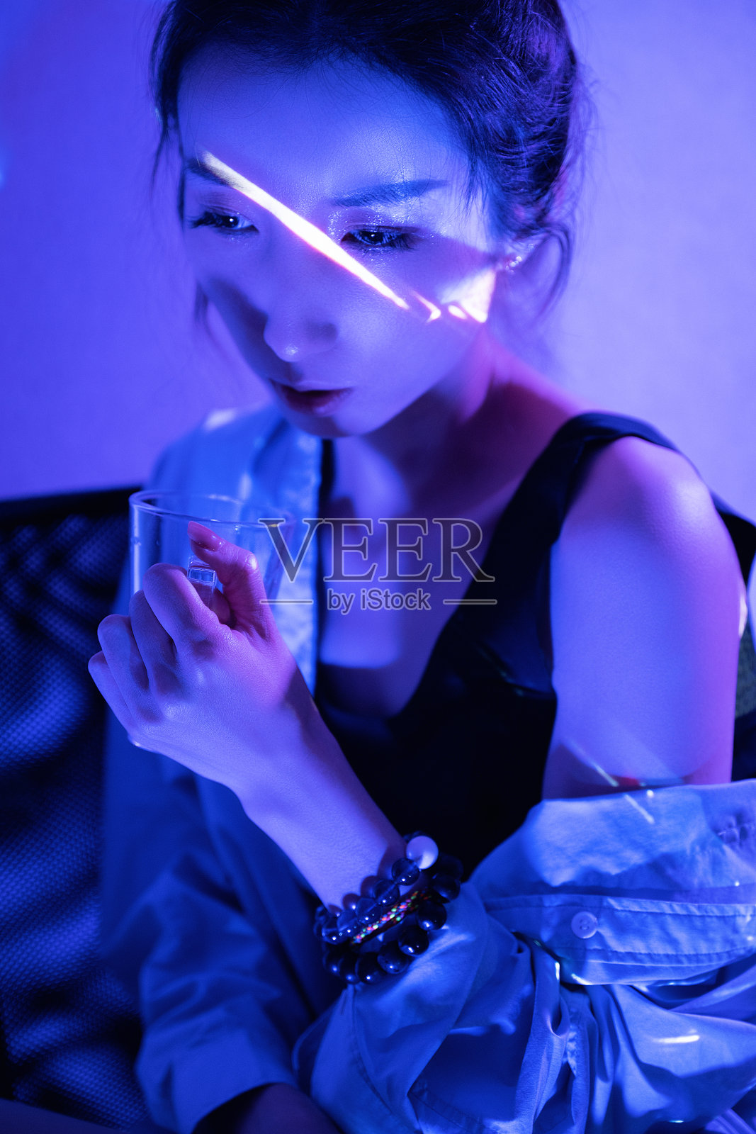 霓虹灯照在拿着透明眼镜的美女身上照片摄影图片