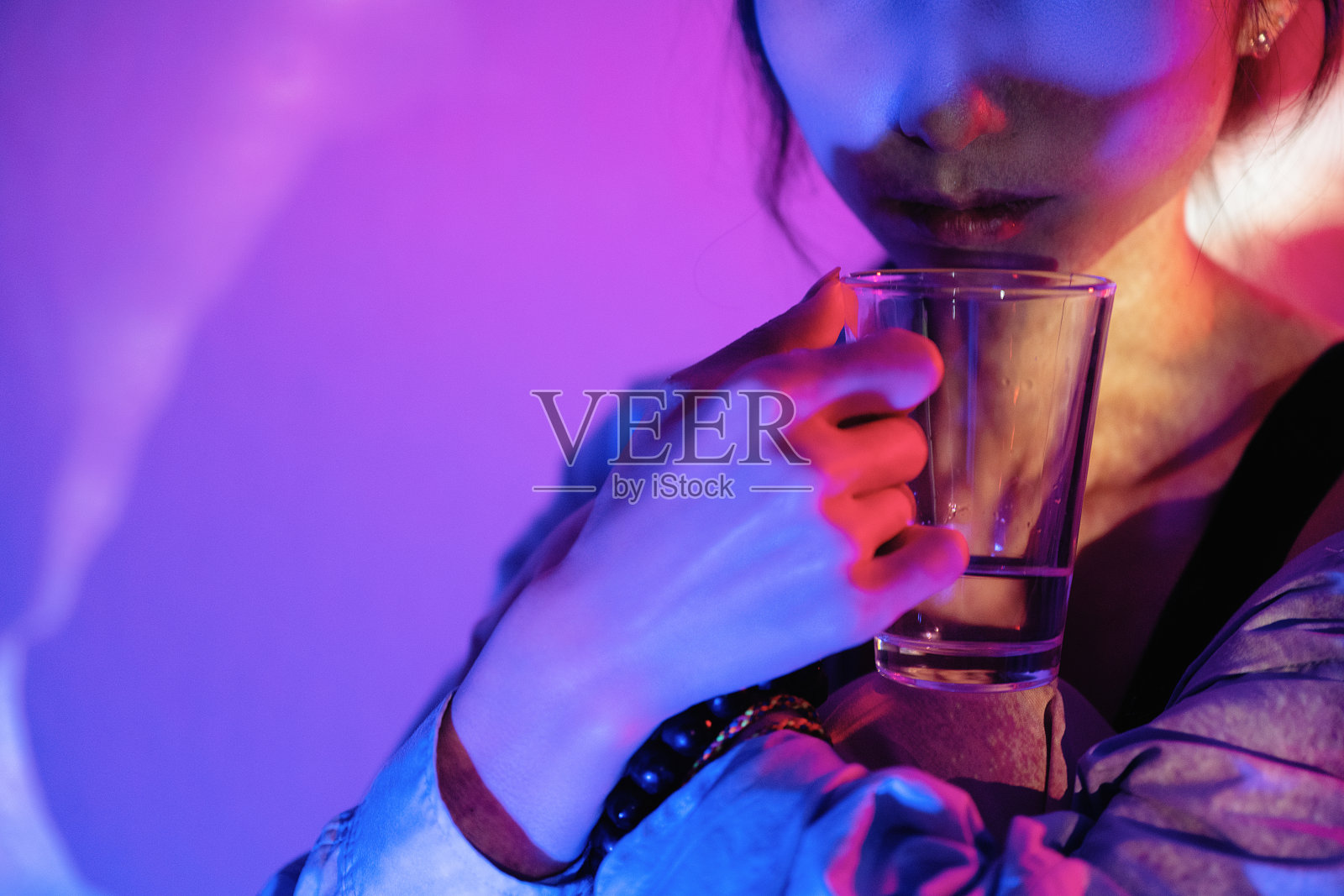 霓虹灯照在拿着透明眼镜的美女身上照片摄影图片