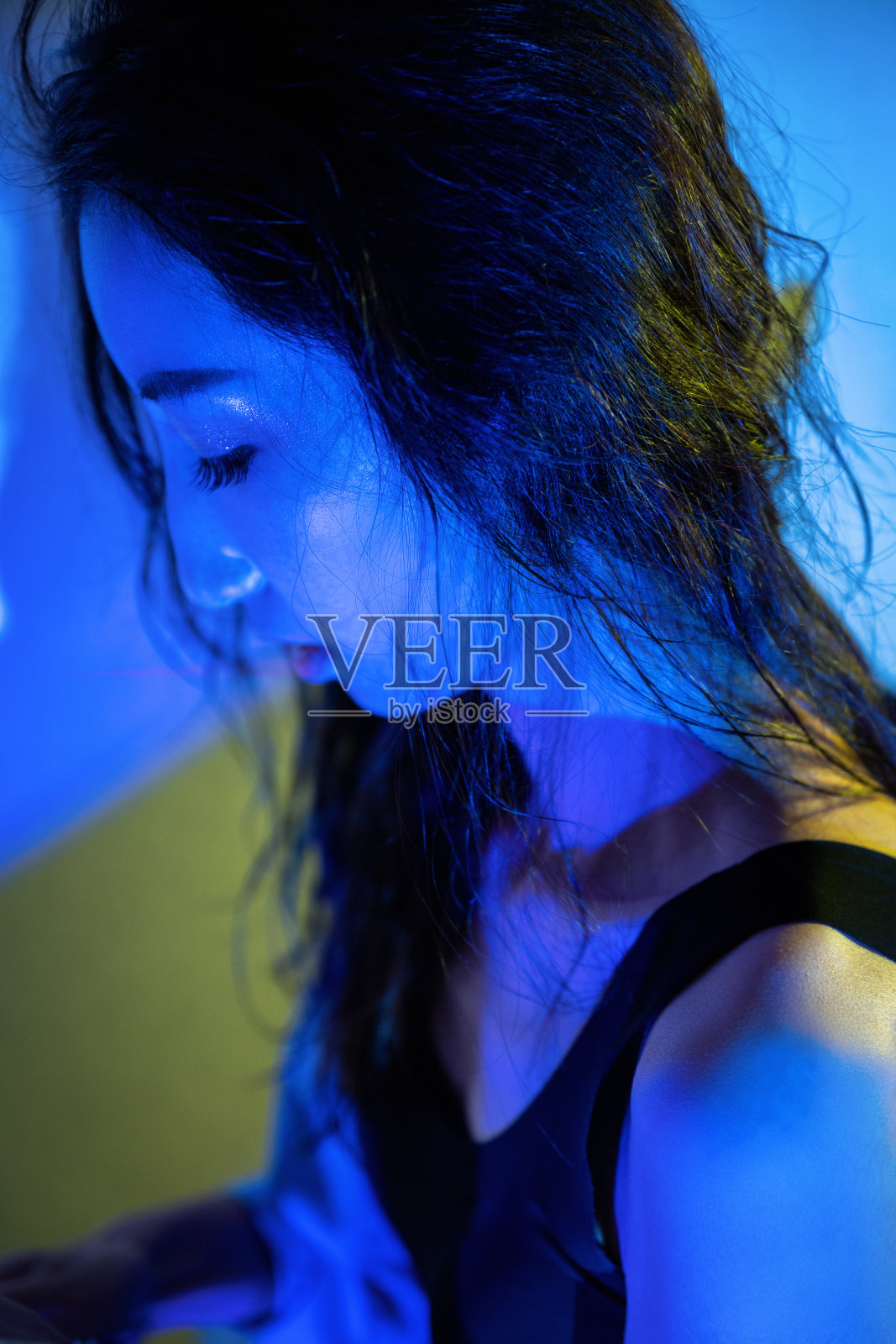 霓虹灯照在用吹风机吹头发的美女脸上照片摄影图片