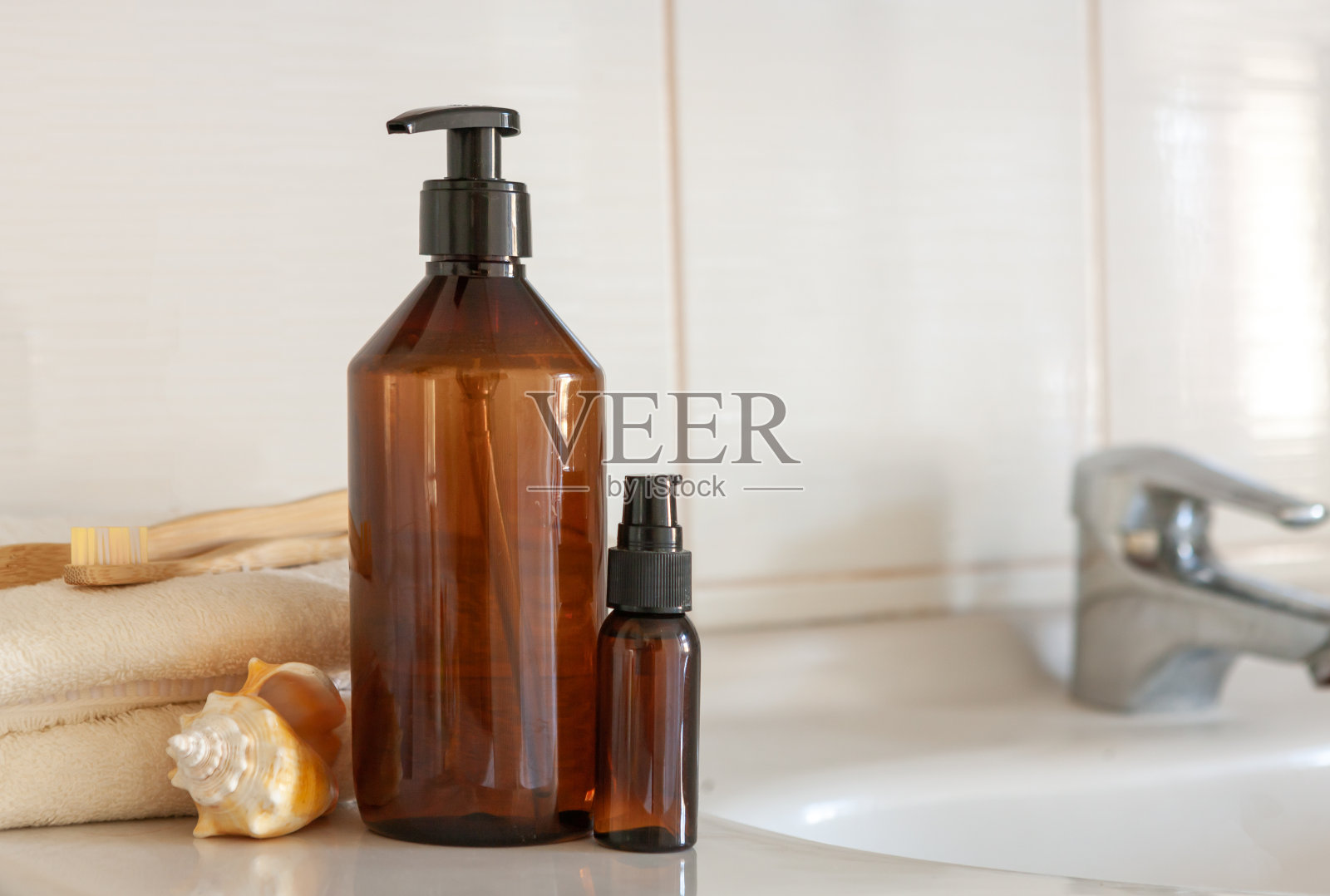 贝壳，浴白色棉花毛巾，饮料瓶，竹牙刷模糊浴室内部背景与水槽和水龙头照片摄影图片