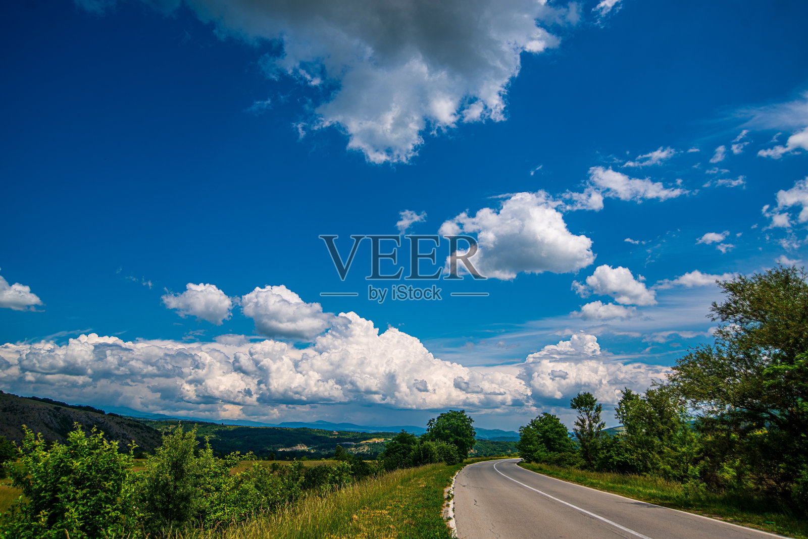 从空中俯瞰山谷中的道路、沥青路面和长满绿草的草地。照片摄影图片