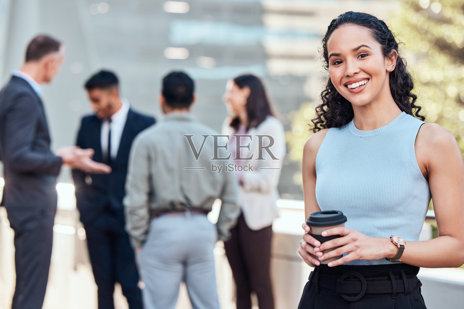 照片中，一位漂亮的年轻女商人站在外面，她的同事们站在她身后照片摄影图片