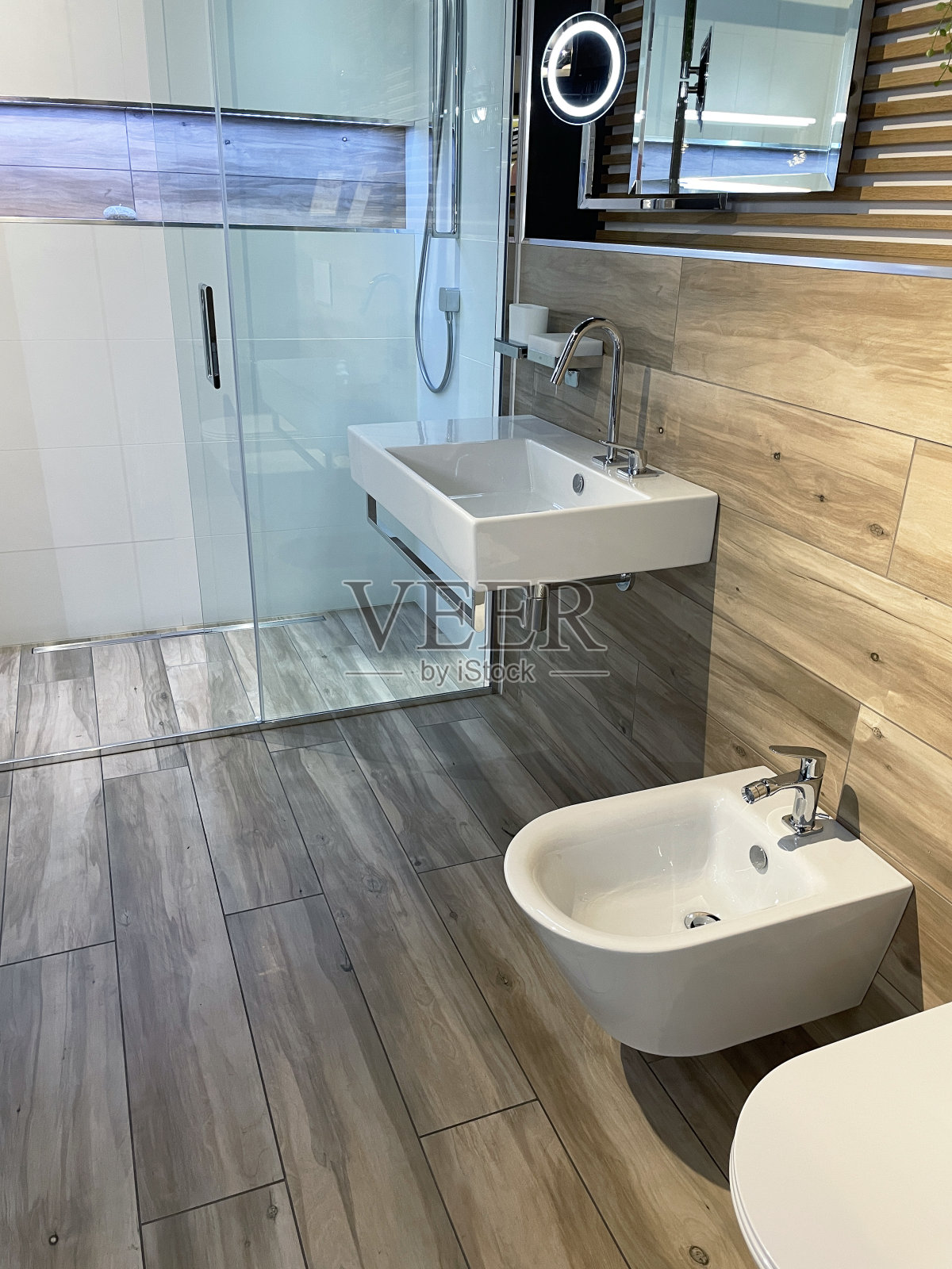 形象的瑞典风格浴室套房，白色墙壁悬挂的坐浴盆和马桶，矩形水槽下挂铬毛巾栏杆，独立的淋浴间，滑动，镶板玻璃门，头顶，矩形电源淋浴器，墙上挂定向淋浴器照片摄影图片