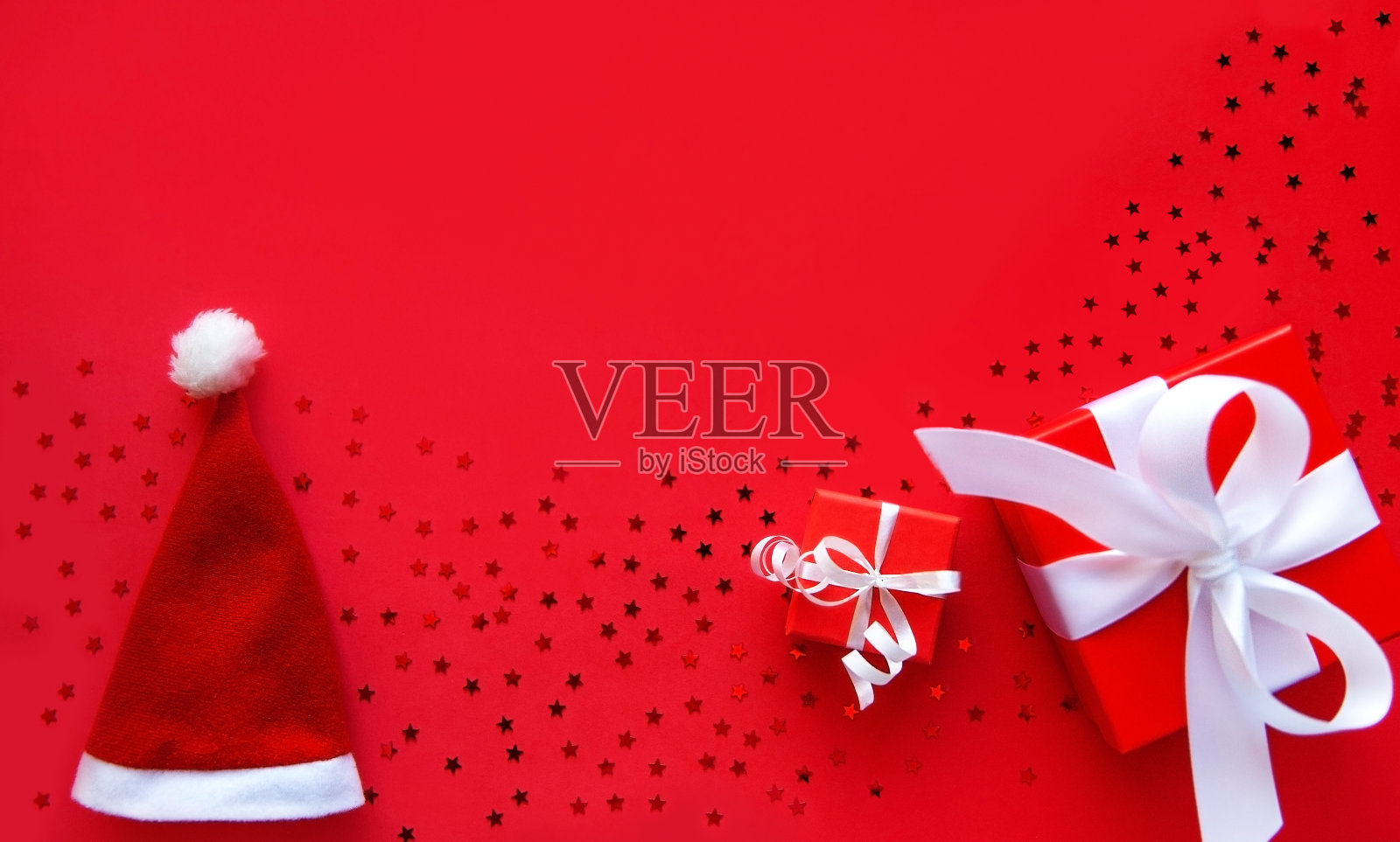 圣诞礼物和圣诞老人帽子上的红色背景照片摄影图片