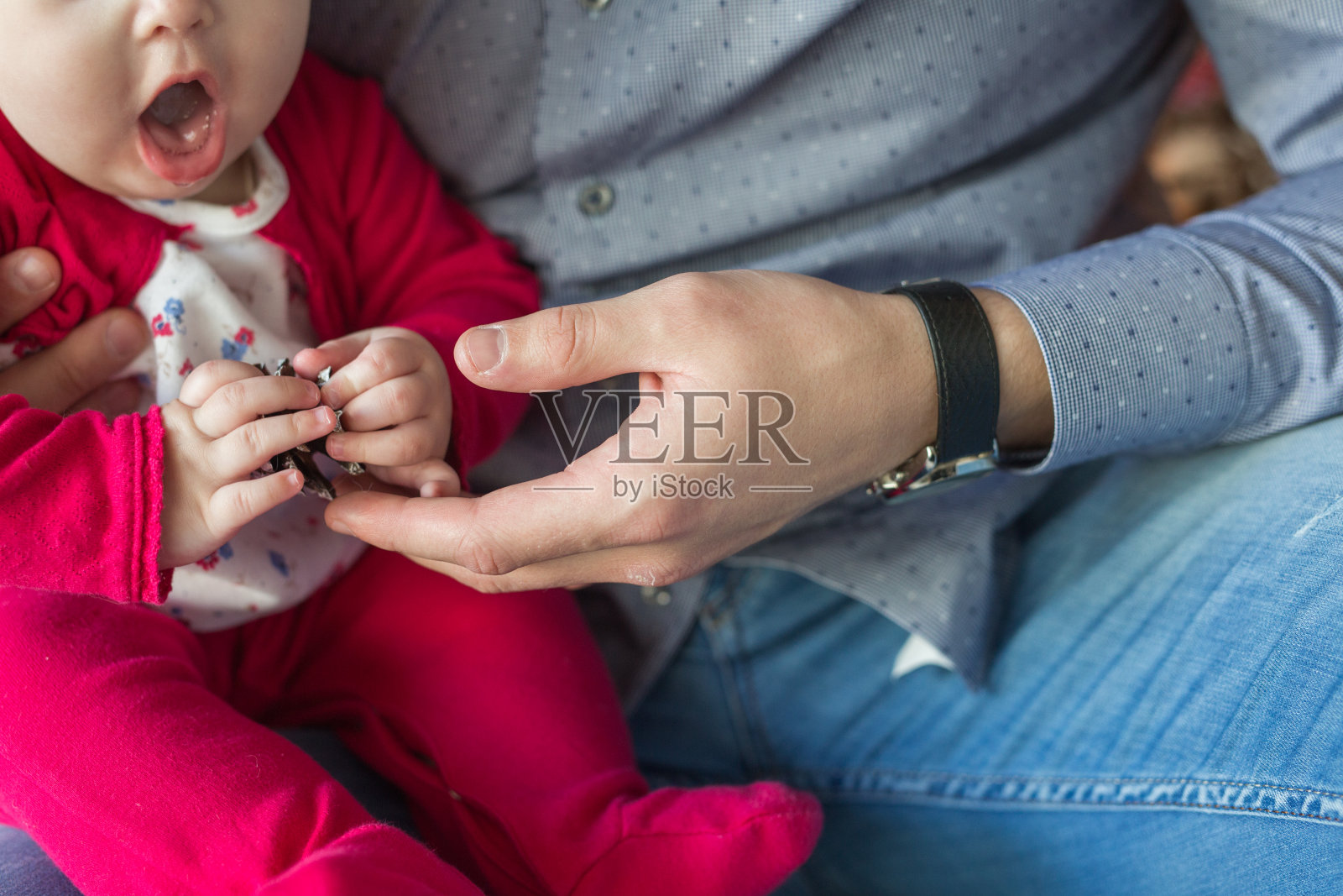 年轻的父亲把小女儿抱在怀里，和她一起玩耍。一个男人怀里抱着一个女孩。概念——圣诞节假期。照片摄影图片