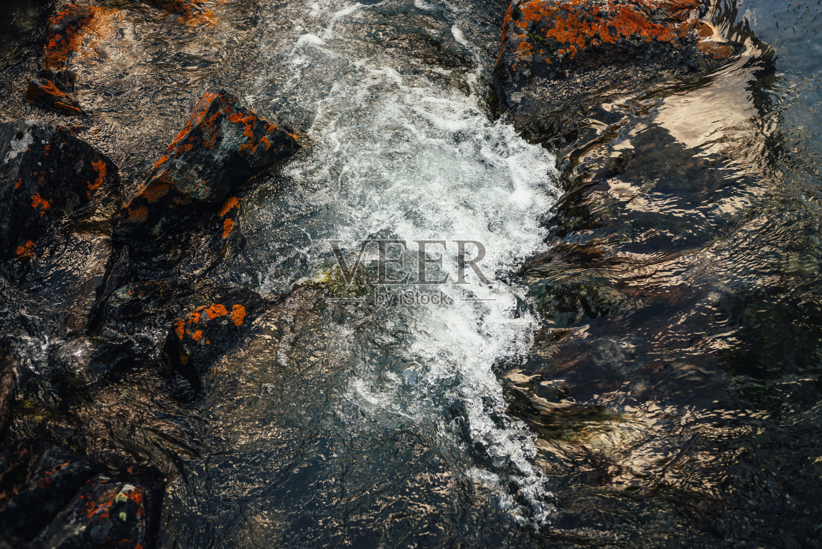 风景自然的背景，清澈的水与岩石与橙色的地衣。山溪清澈的水中有青苔石，山景大气。美丽的山流。照片摄影图片