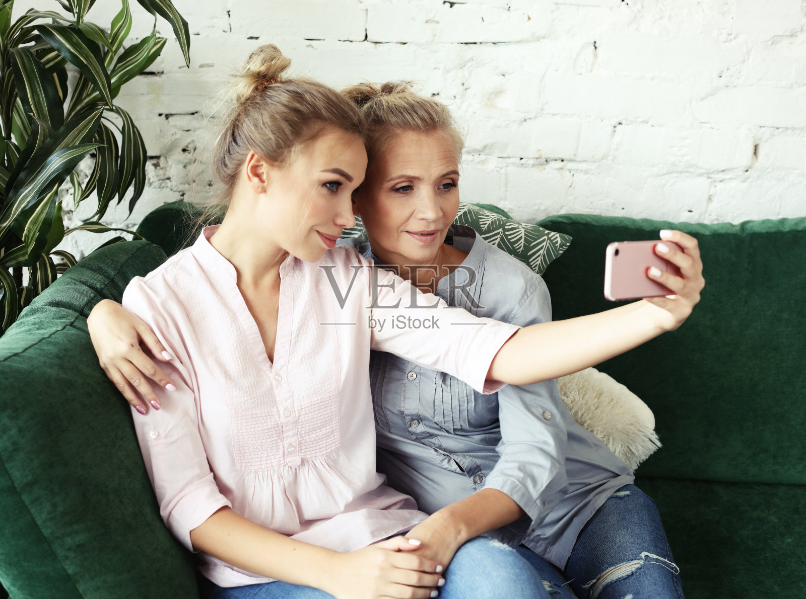 美丽成熟的母亲和女儿用智能手机自拍，微笑着，家和快乐照片摄影图片