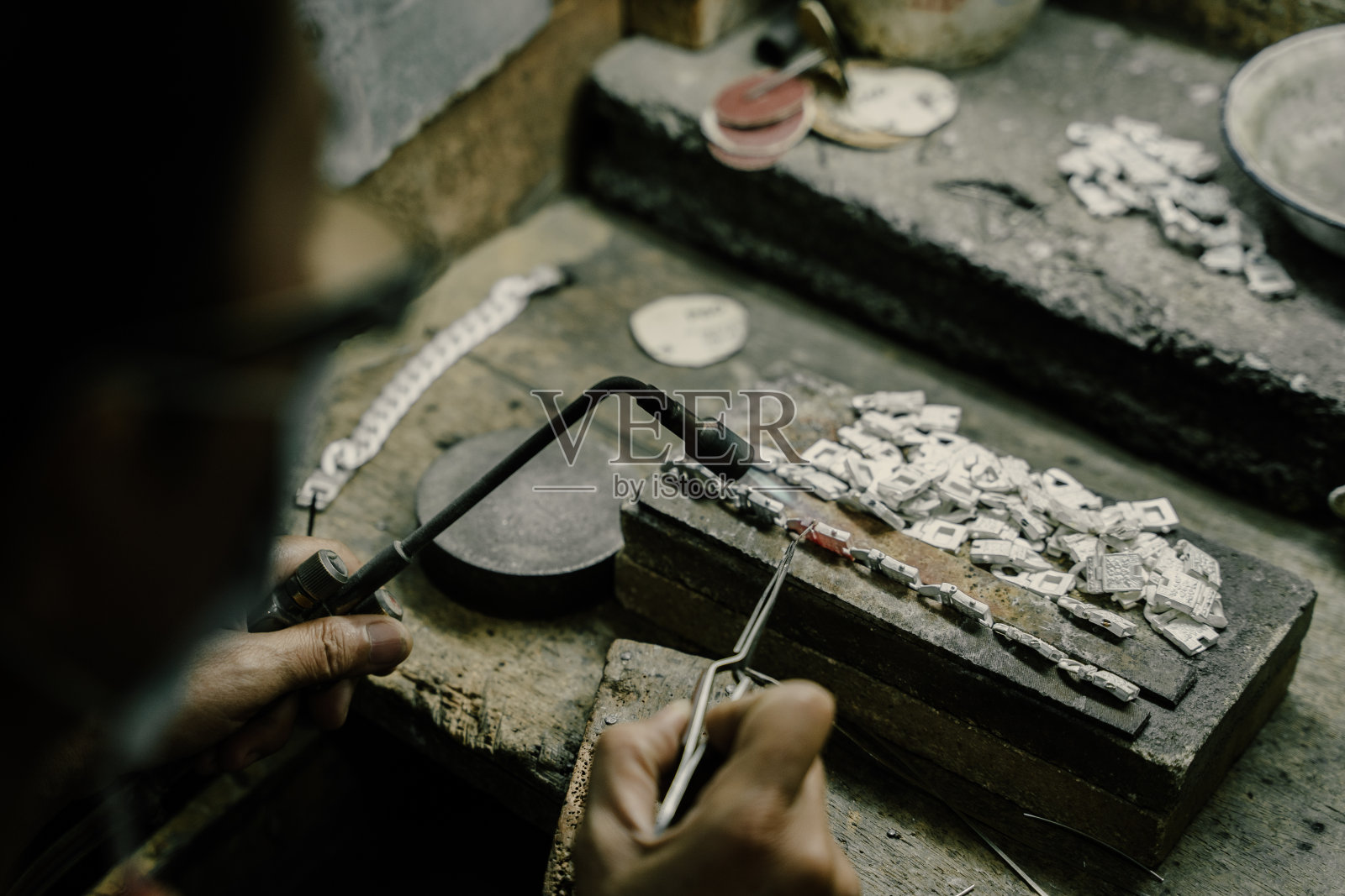 珠宝商在珠宝行业工作。用专业工具制作工艺首饰的桌面。近距离查看工具。银首饰。照片摄影图片