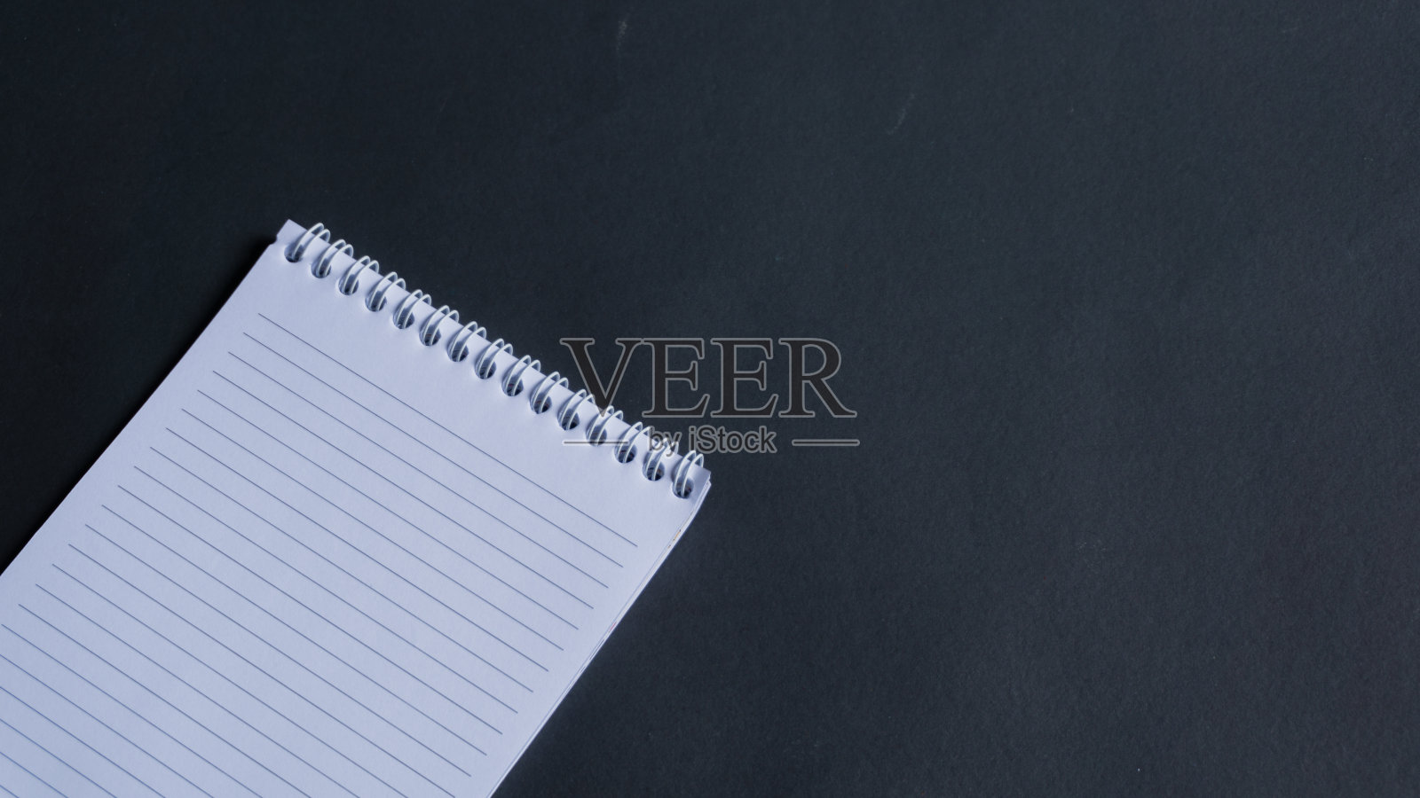 最小的工作空间，在黑色背景上的笔记本的顶部视图。笔记本复制空间和文本空间照片摄影图片