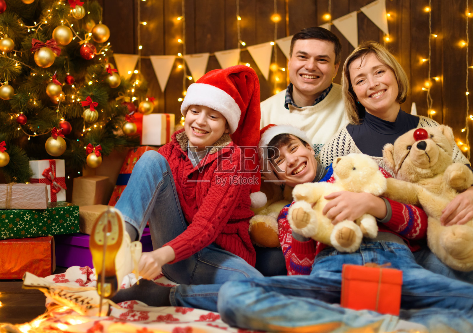 家庭在新年或圣诞节的装饰。孩子和父母。节日彩灯和礼物。木制背景照明。用玩具装饰的圣诞树。照片摄影图片