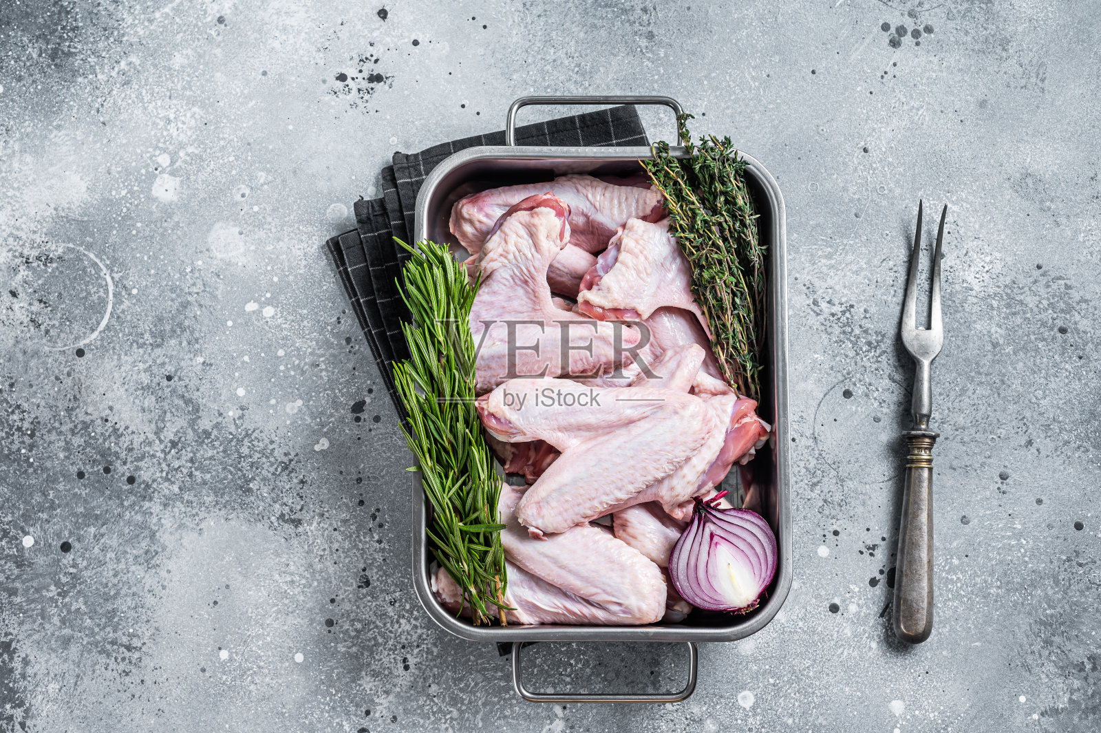 钢盘盛着生鸭翅。灰色的背景。俯视图照片摄影图片