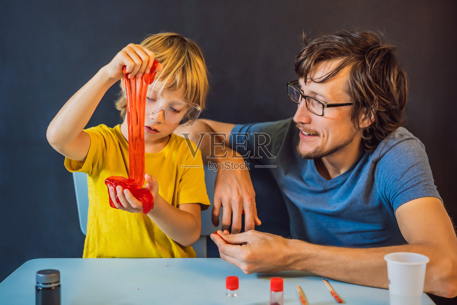 父亲和儿子在家里进行化学实验。家里做的黏液。家人玩黏液照片摄影图片