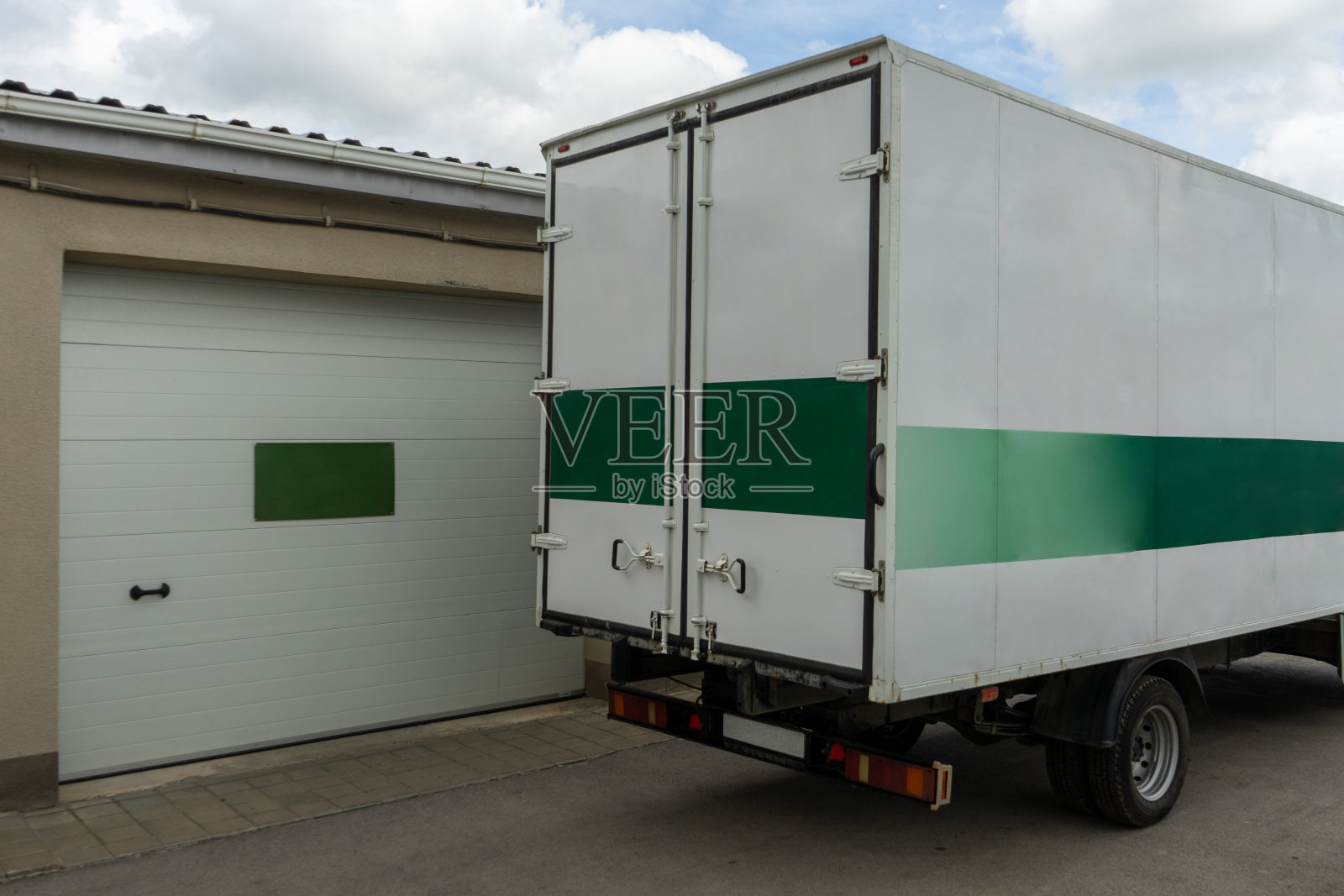 一辆卡车驶进了一座装有装卸货物大门的建筑物。生产物流。照片摄影图片