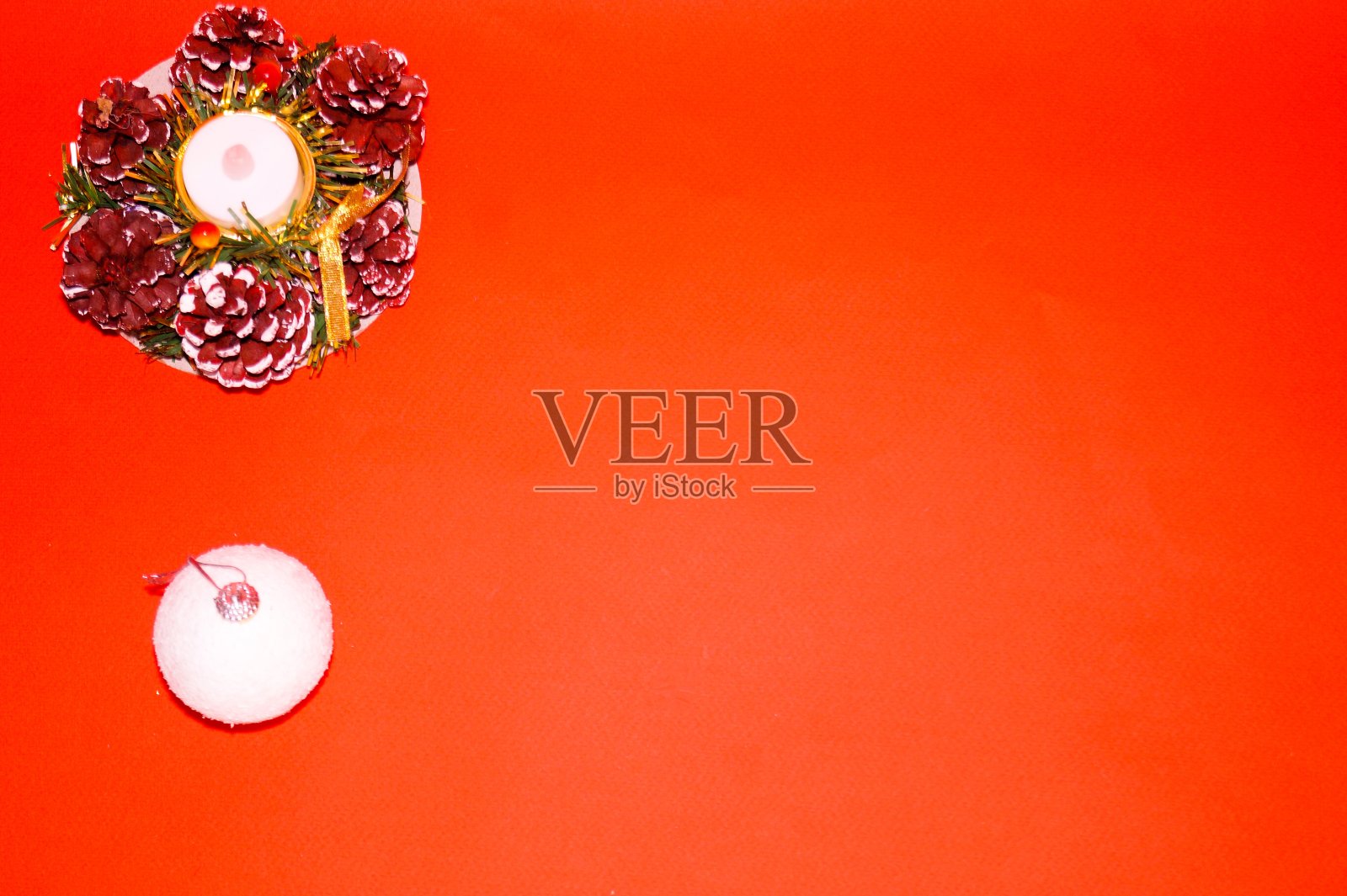 新年的布局在红色的背景是一个白色的球和一个圆锥形的组成和一支蜡烛。照片摄影图片