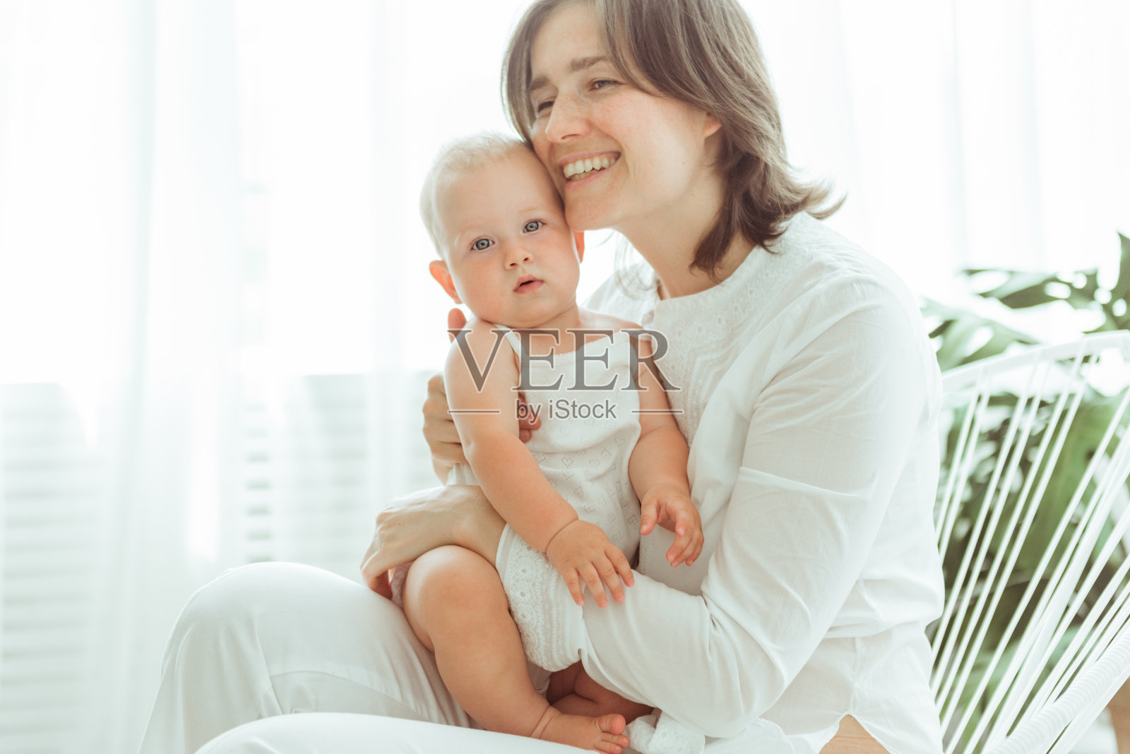 无条件的爱。一名年轻女子坐在家里的床上，和她刚出生的孩子亲密无间照片摄影图片