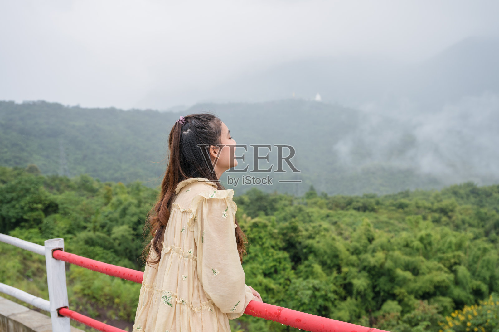 亚洲女人放松和看与雾蒙蒙的山景在雨季照片摄影图片