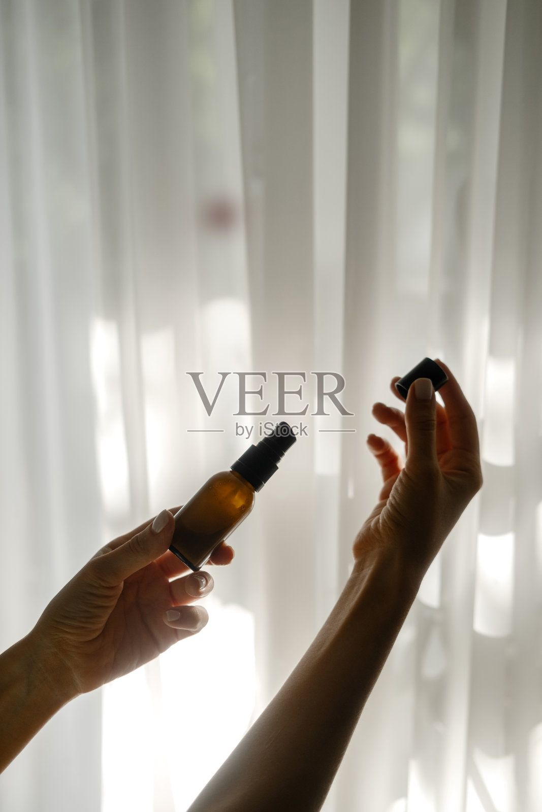 女人手里拿着化妆用的棕色玻璃瓶照片摄影图片