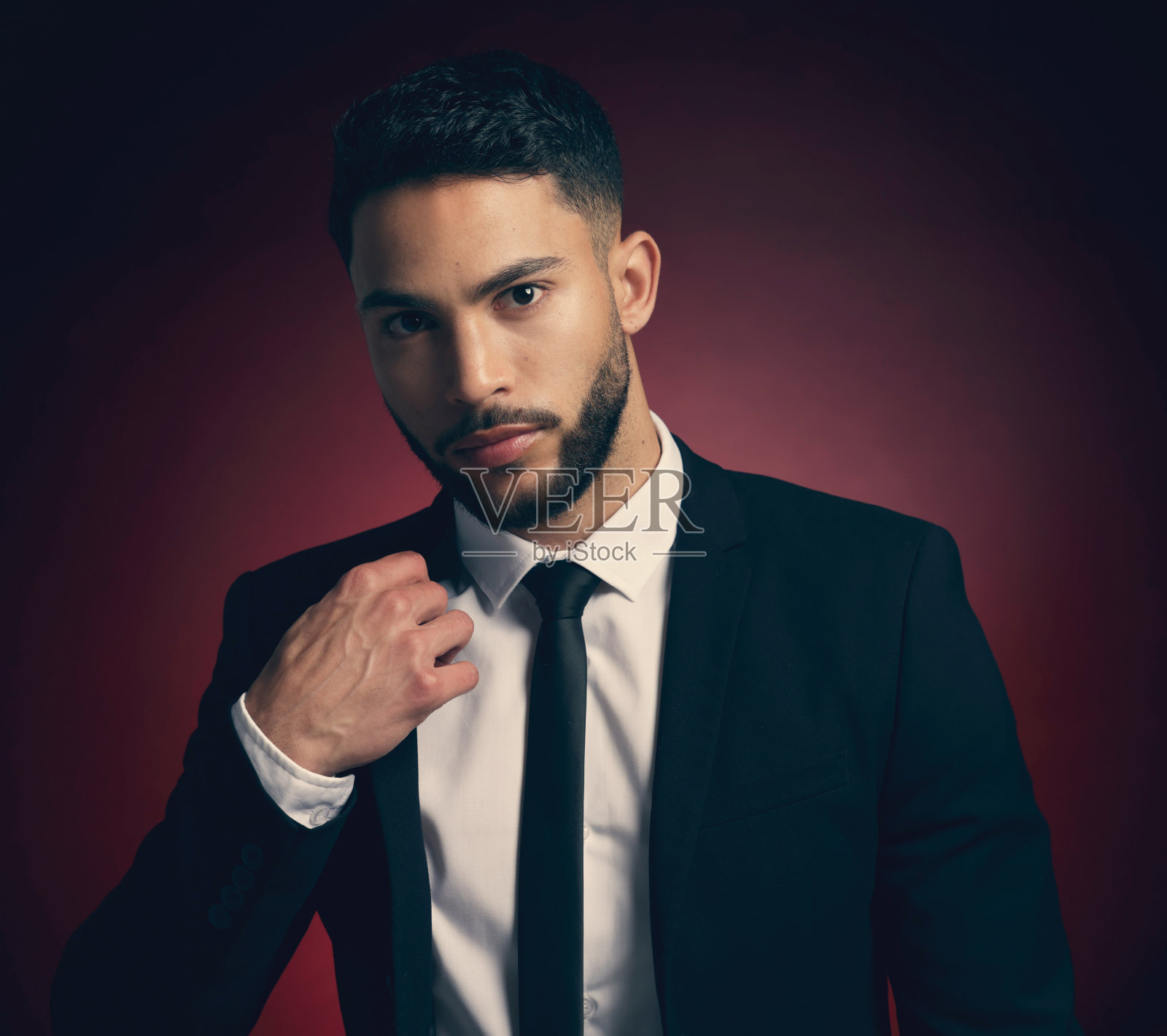 摄影棚里一个年轻男子在红色背景下摆姿势照片摄影图片