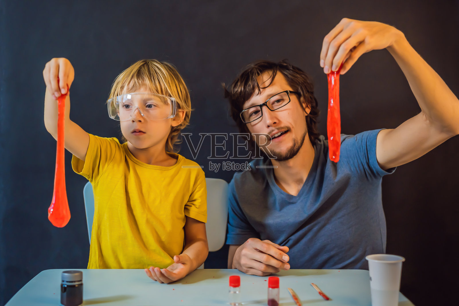 父亲和儿子在家里进行化学实验。家里做的黏液。家人玩黏液照片摄影图片