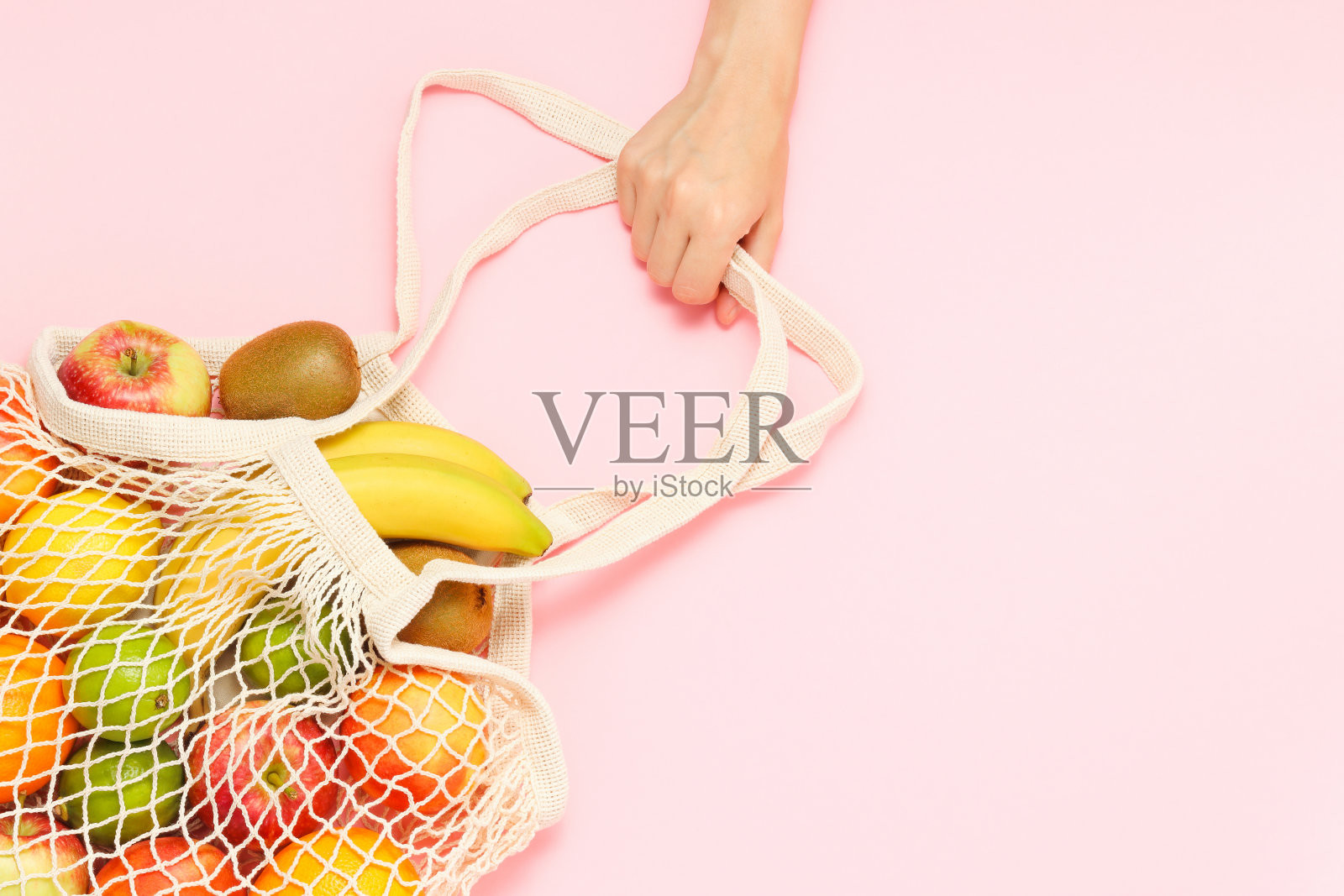 女手拿细绳购物袋装满新鲜水果照片摄影图片