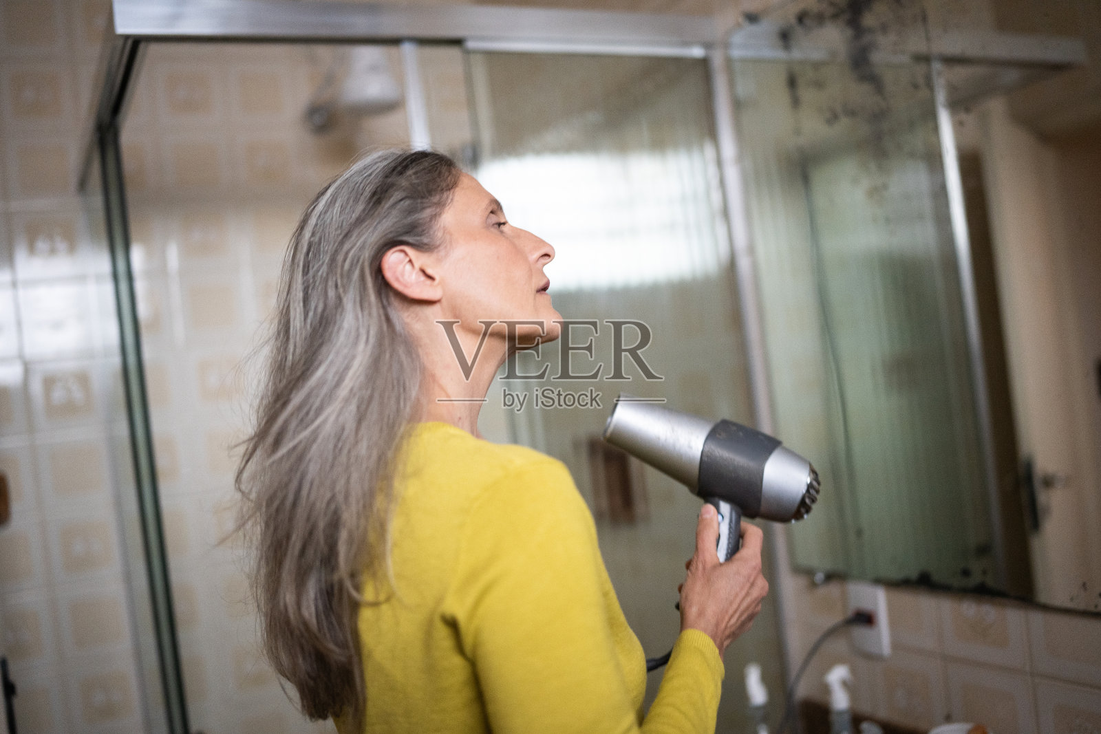 成熟的女人在家吹干头发照片摄影图片